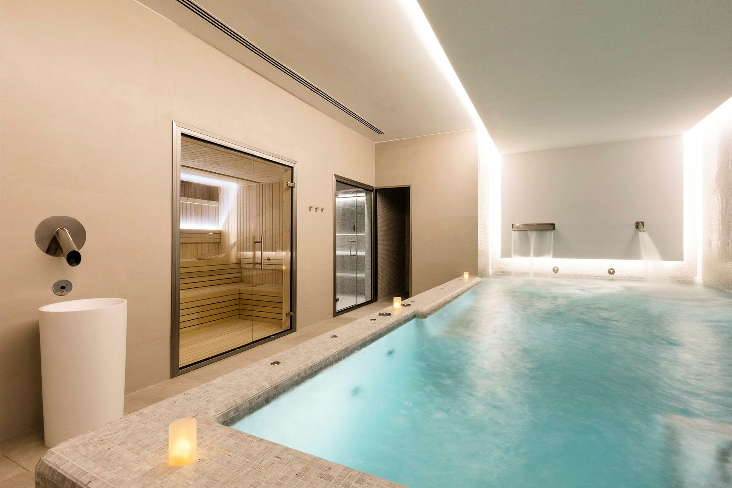 En interiörbild av ett spa med en uppvärmd pool, en bastu och en duschgelegenhet. (AI-genererad text)