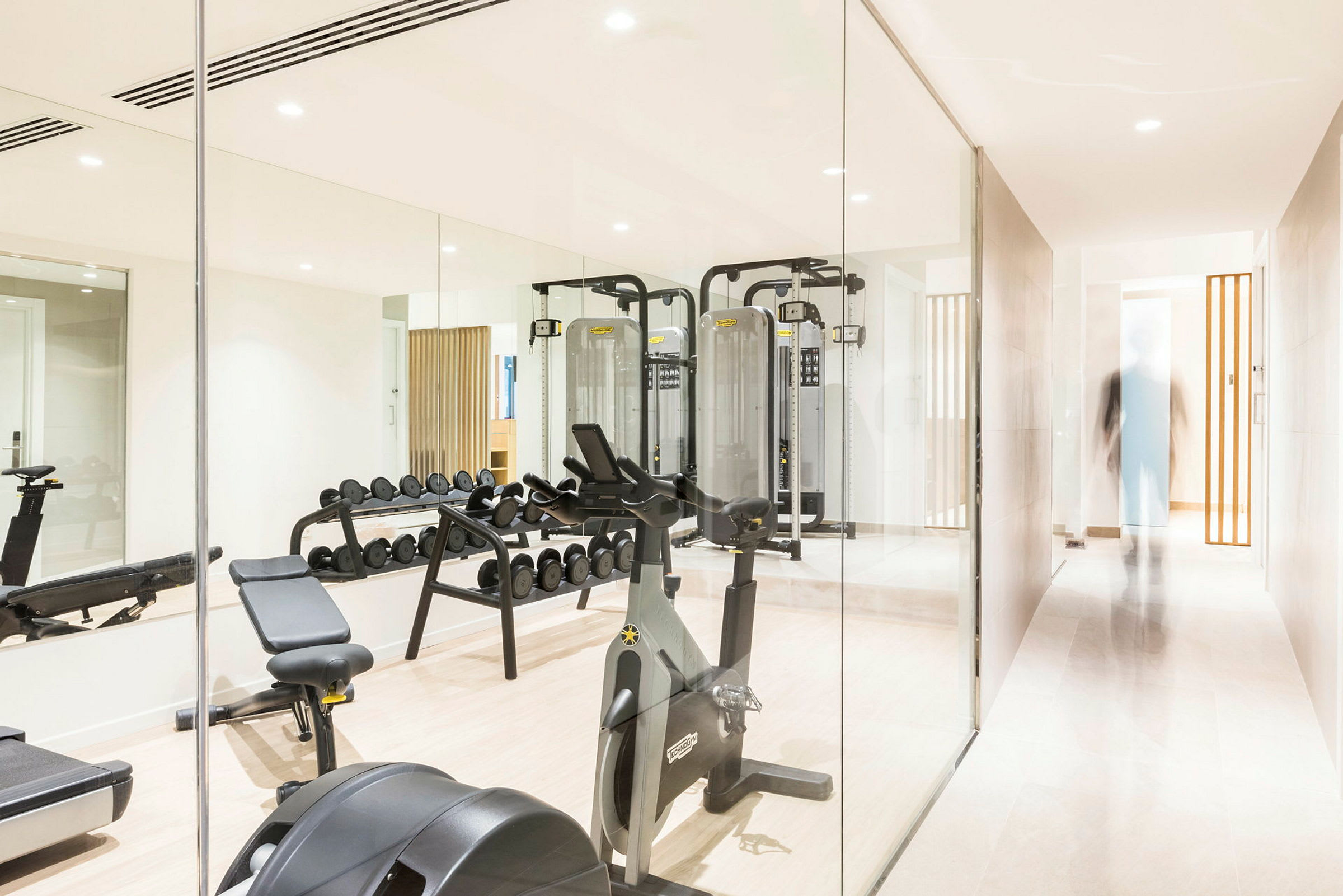 Gym med olika träningsmaskiner och spegelvägg. (AI-genererad text)