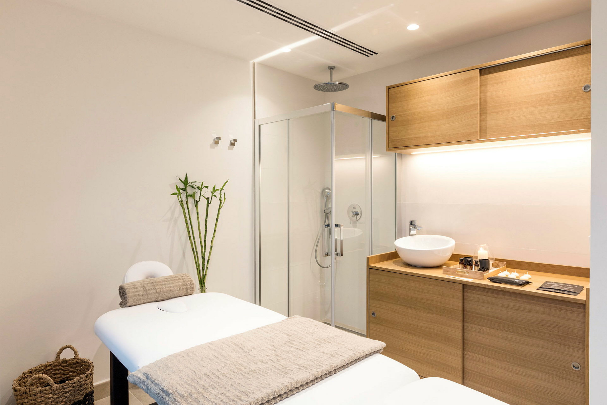 Ett modernt spa-rum med en massagebänk, bambu-dekoration och ett handfat i träinredning. (AI-genererad text)