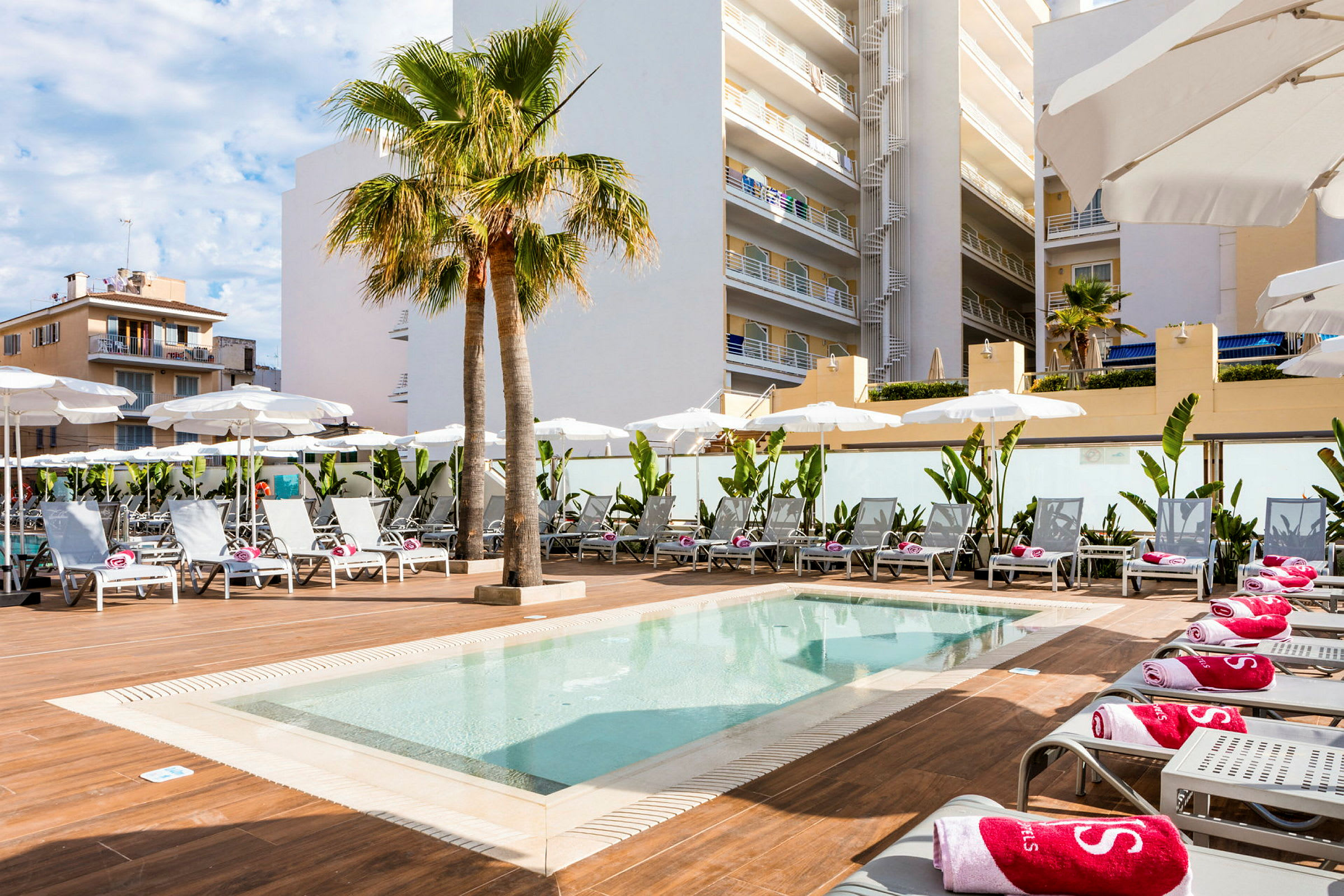 En pool med solstolar och parasoller vid ett hotell. (AI-genererad text)