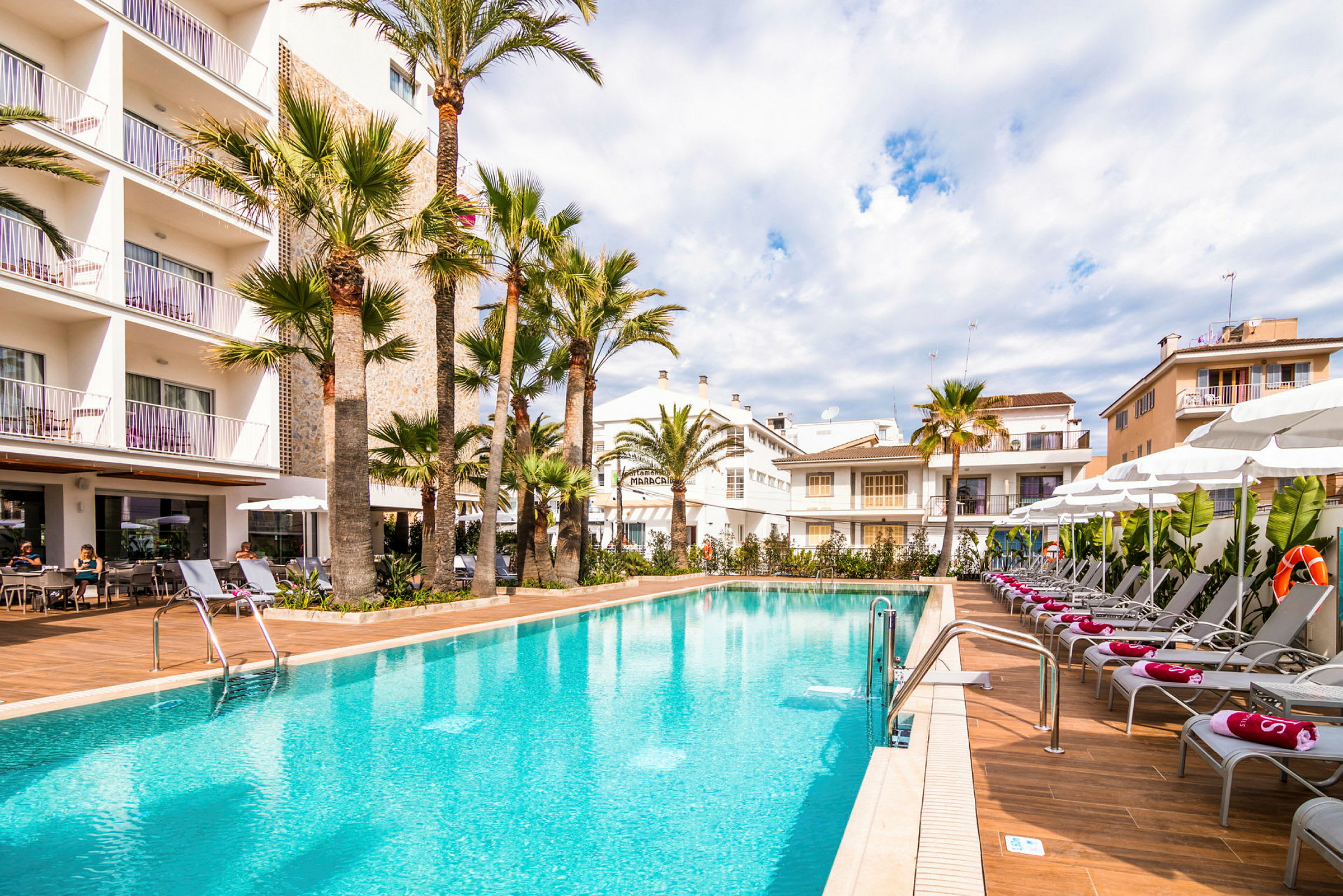 Utomhuspool vid hotell med palmer och solstolar. (AI-genererad text)