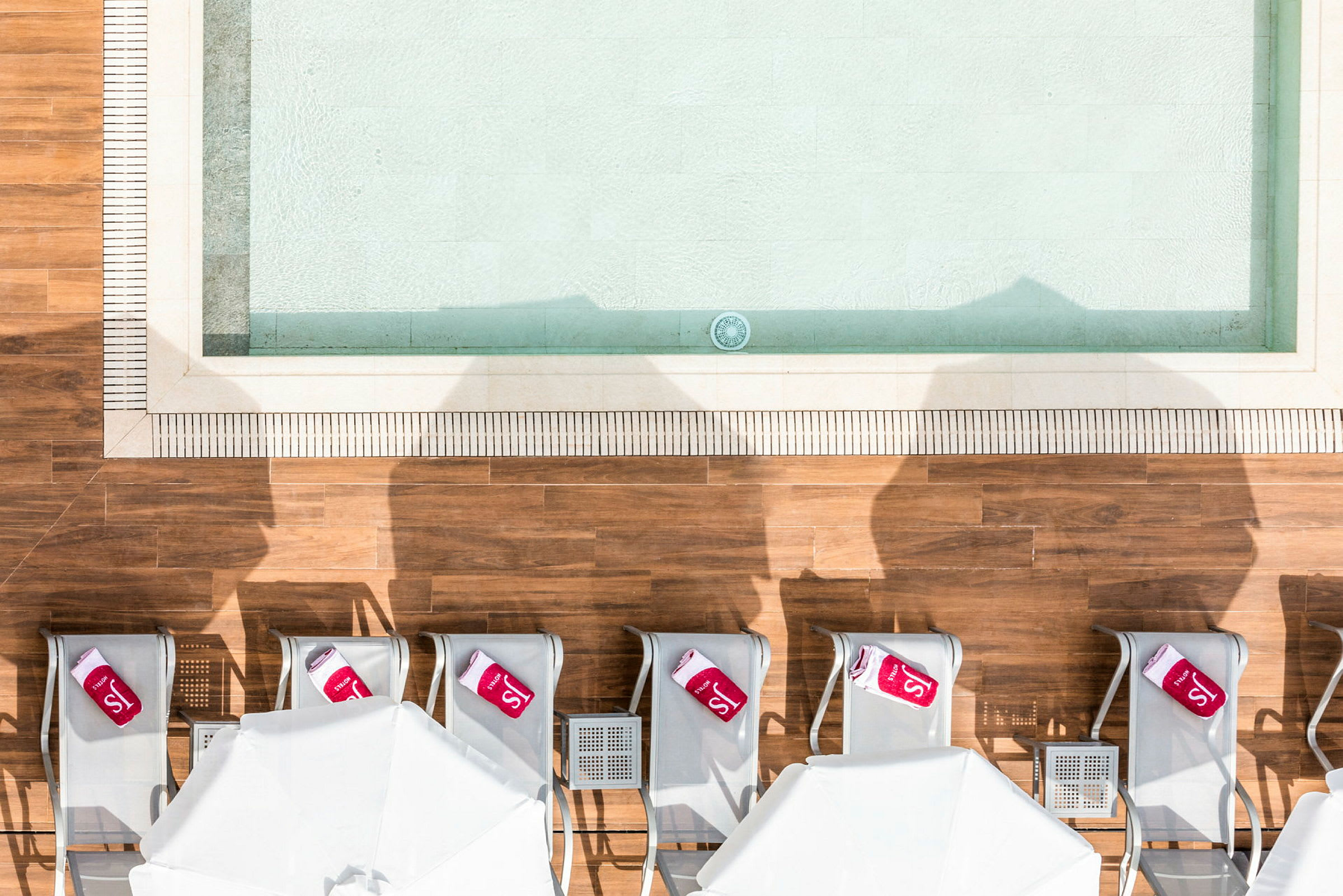 Vy ovanifrån av solstolar och parasoller vid en pool. (AI-genererad text)