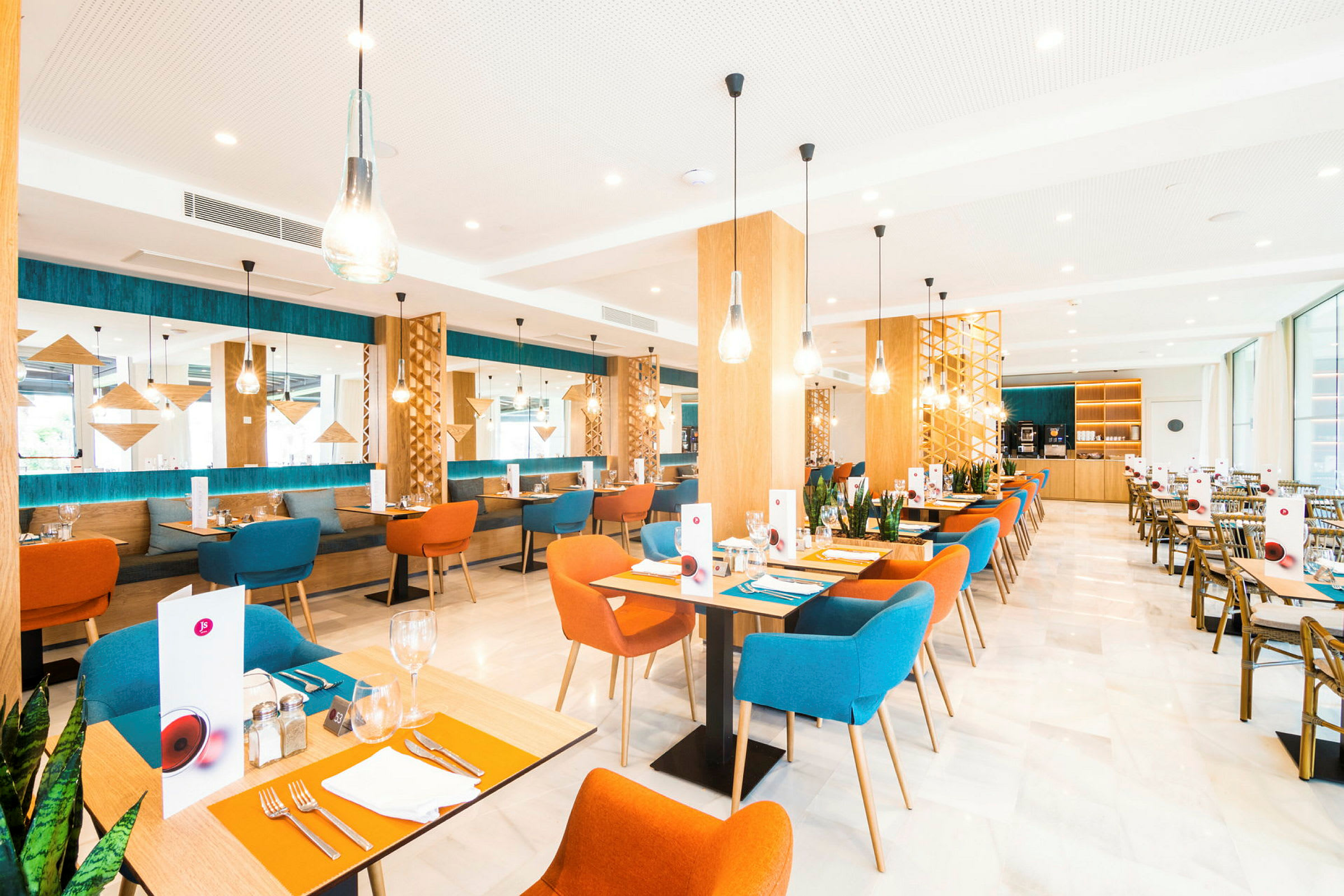 Bild av en modern restaurang med färgglada stolar, träbord och dekorativa ljusarmaturer. (AI-genererad text)