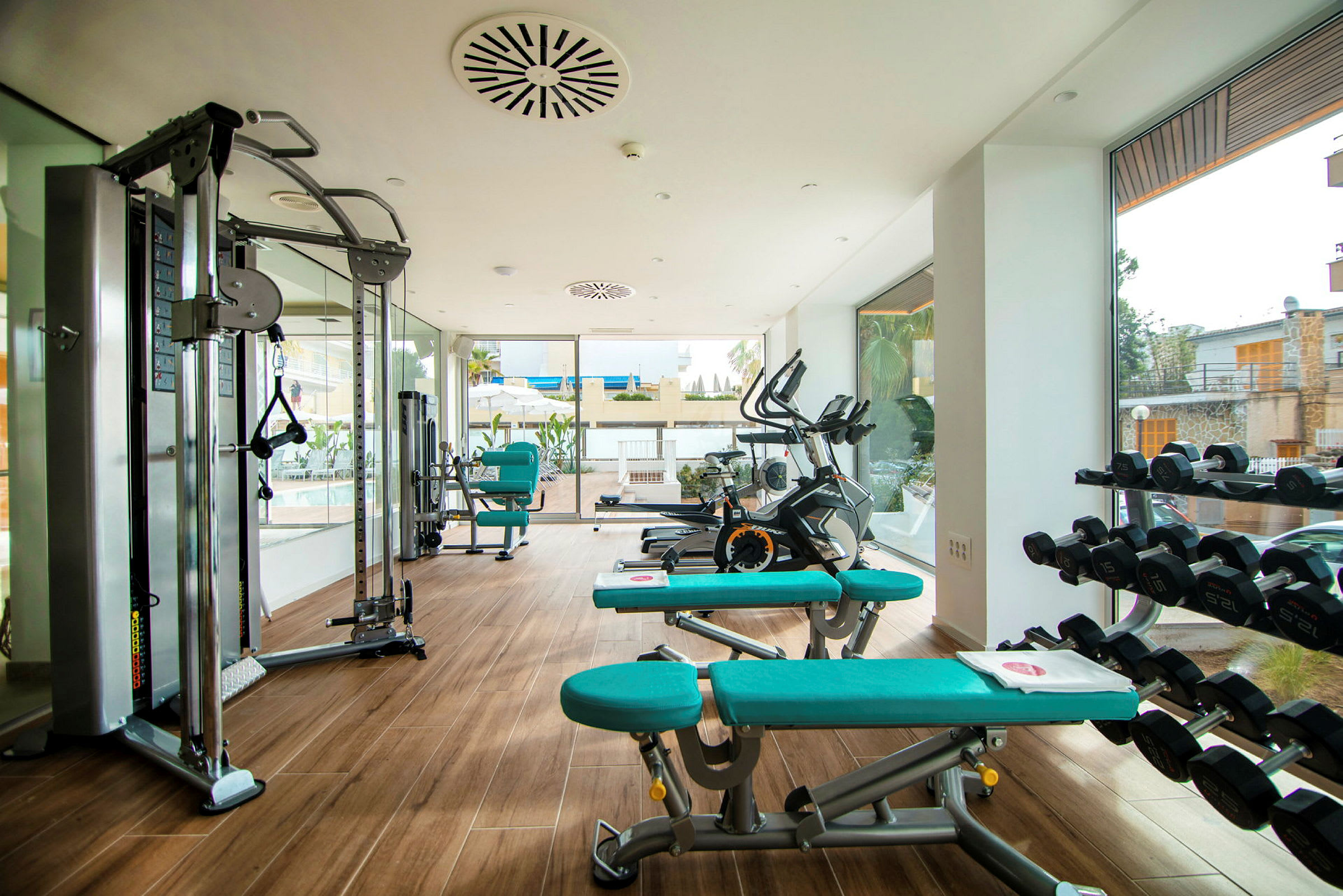 Ett gym med träningsmaskiner, hantlar och bänkar i ett ljus och modernt rum. (AI-genererad text)