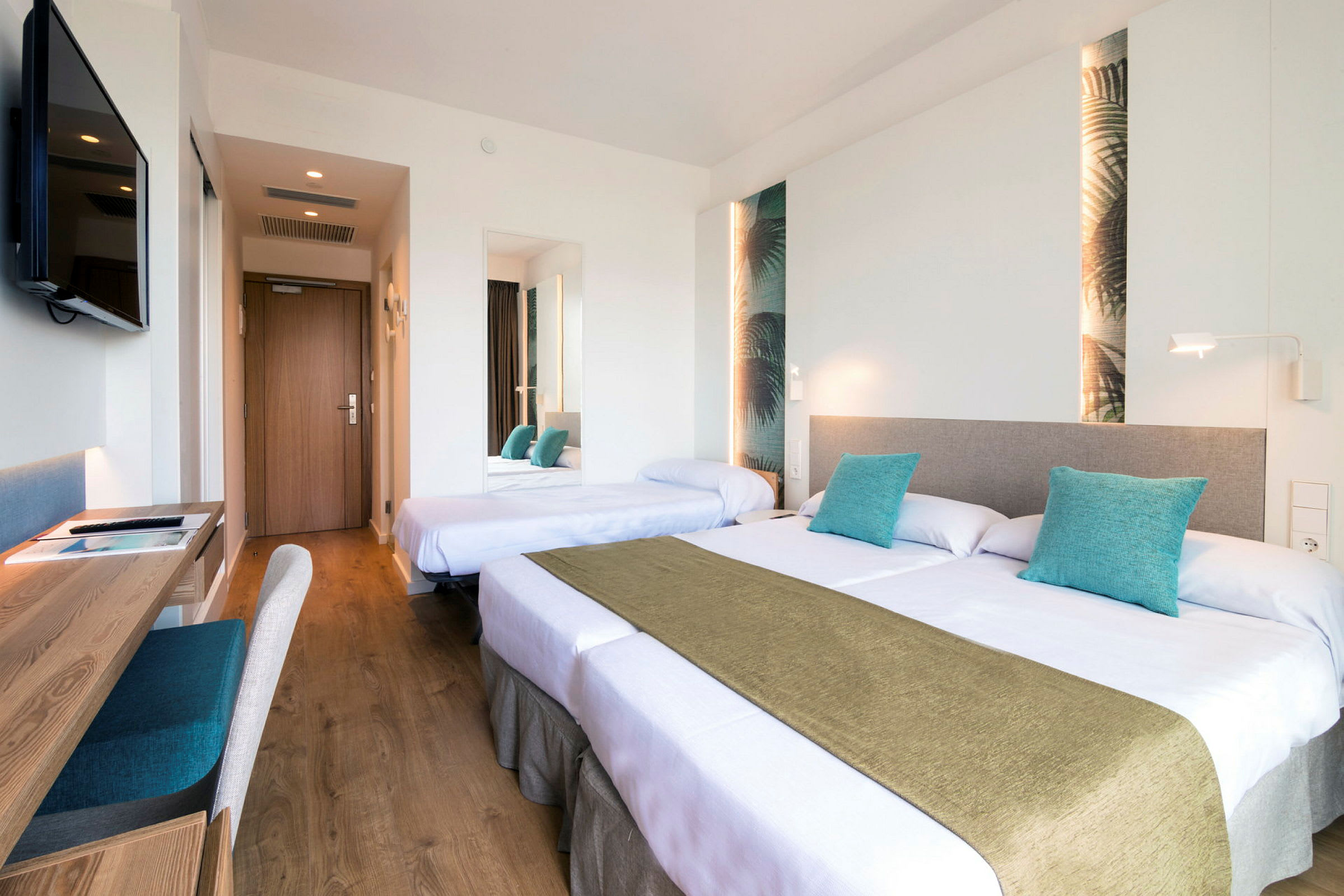 Ett hotellrum med två sängar, skrivbord och en TV monterad på väggen. (AI-genererad text)