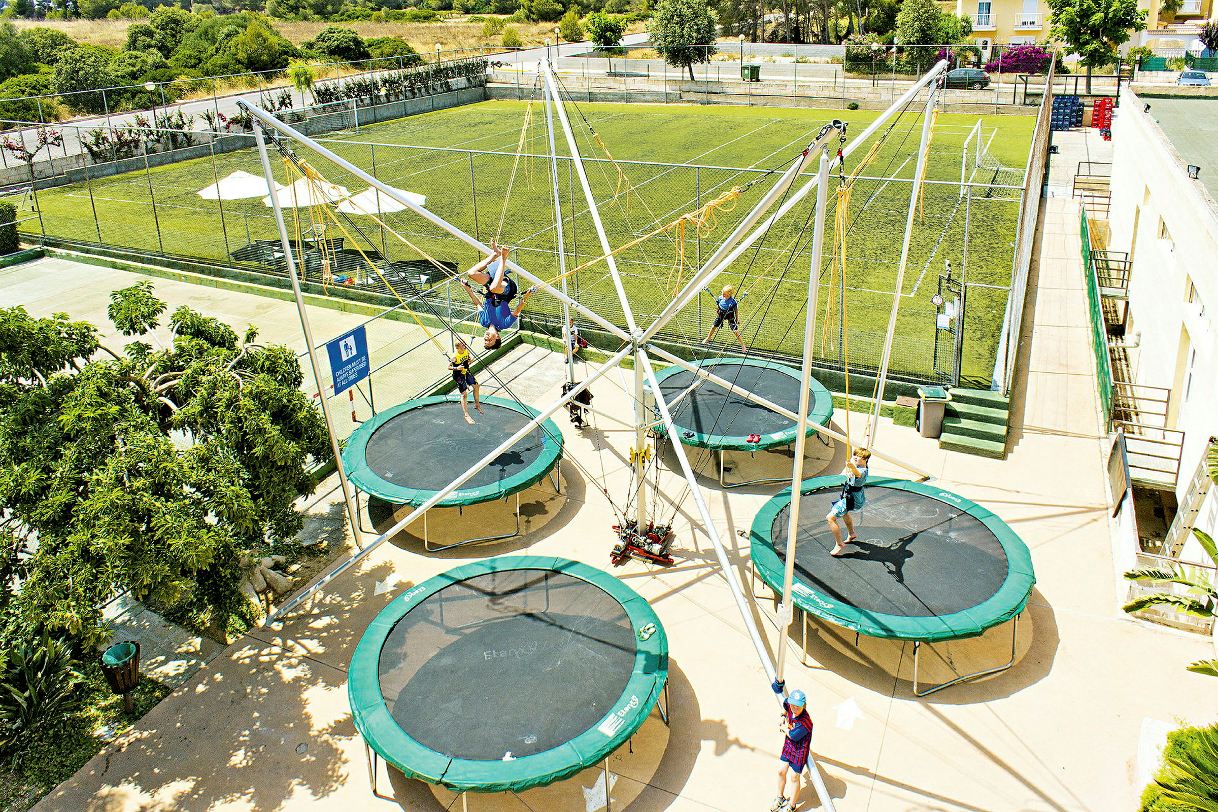Flera personer hoppar på trampoliner i en utomhuspark. (AI-genererad text)