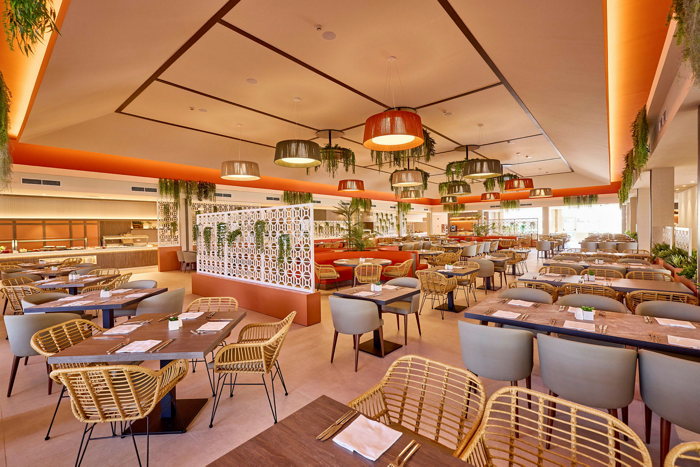 En ljus restaurang med moderna möbler och dekor, inklusive hängande lampor och mycket växter. (AI-genererad text)