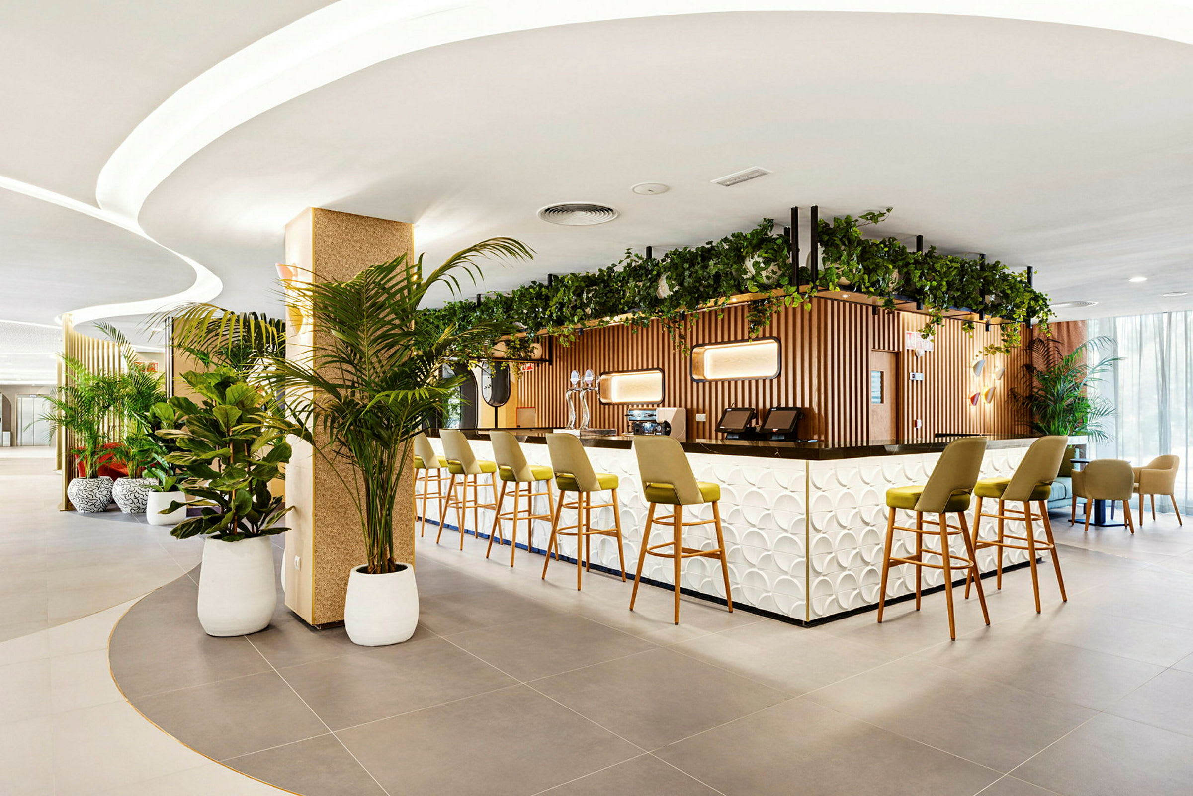 Bild på en modern hotellbar med en stilfull disk och gröna växter. Stolar står uppställda vid bardisken. (AI-genererad text)