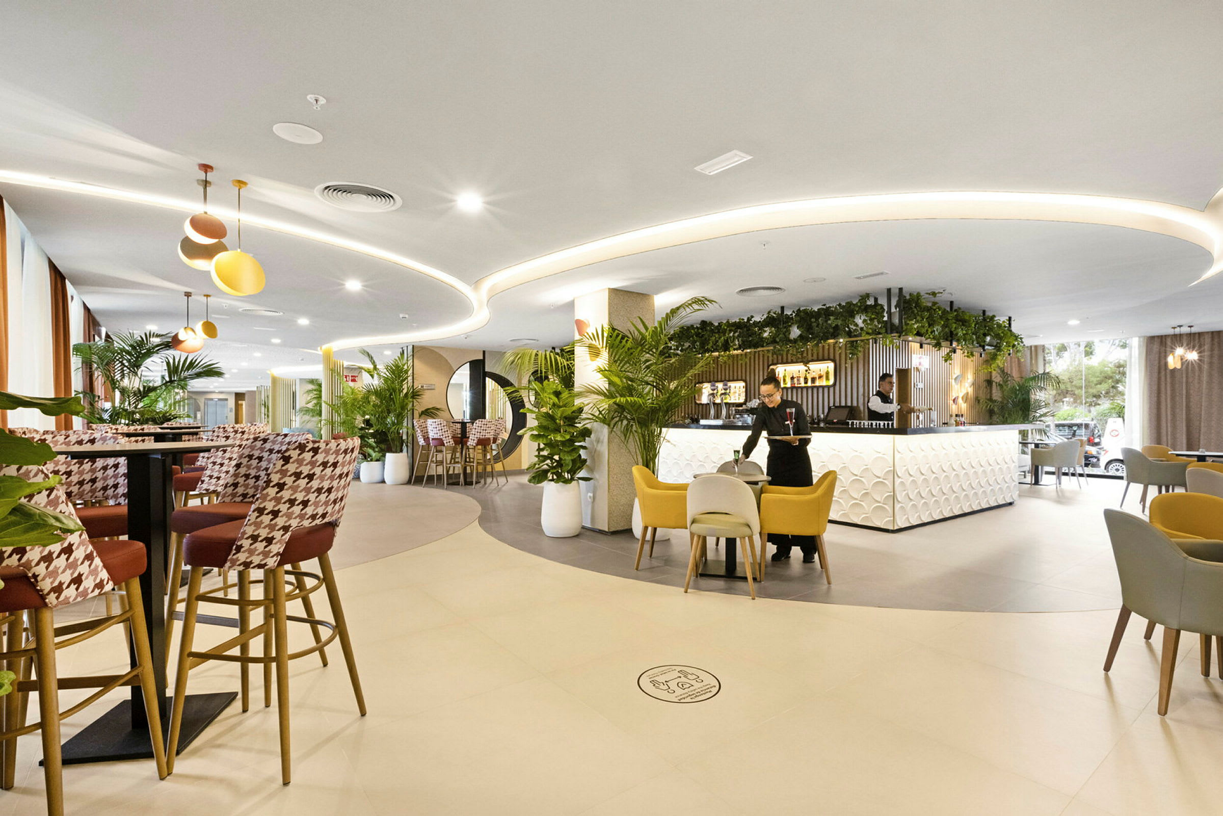 Ett modernt hotellatrium med stilfull inredning, sittplatser och växtdekorationer. (AI-genererad text)