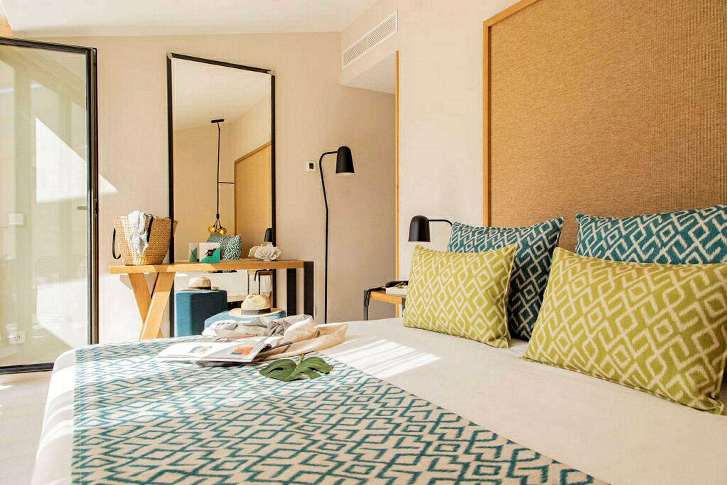 Hotellrum med modern inredning, säng med dekorativa kuddar, spegel och skrivbord. (AI-genererad text)