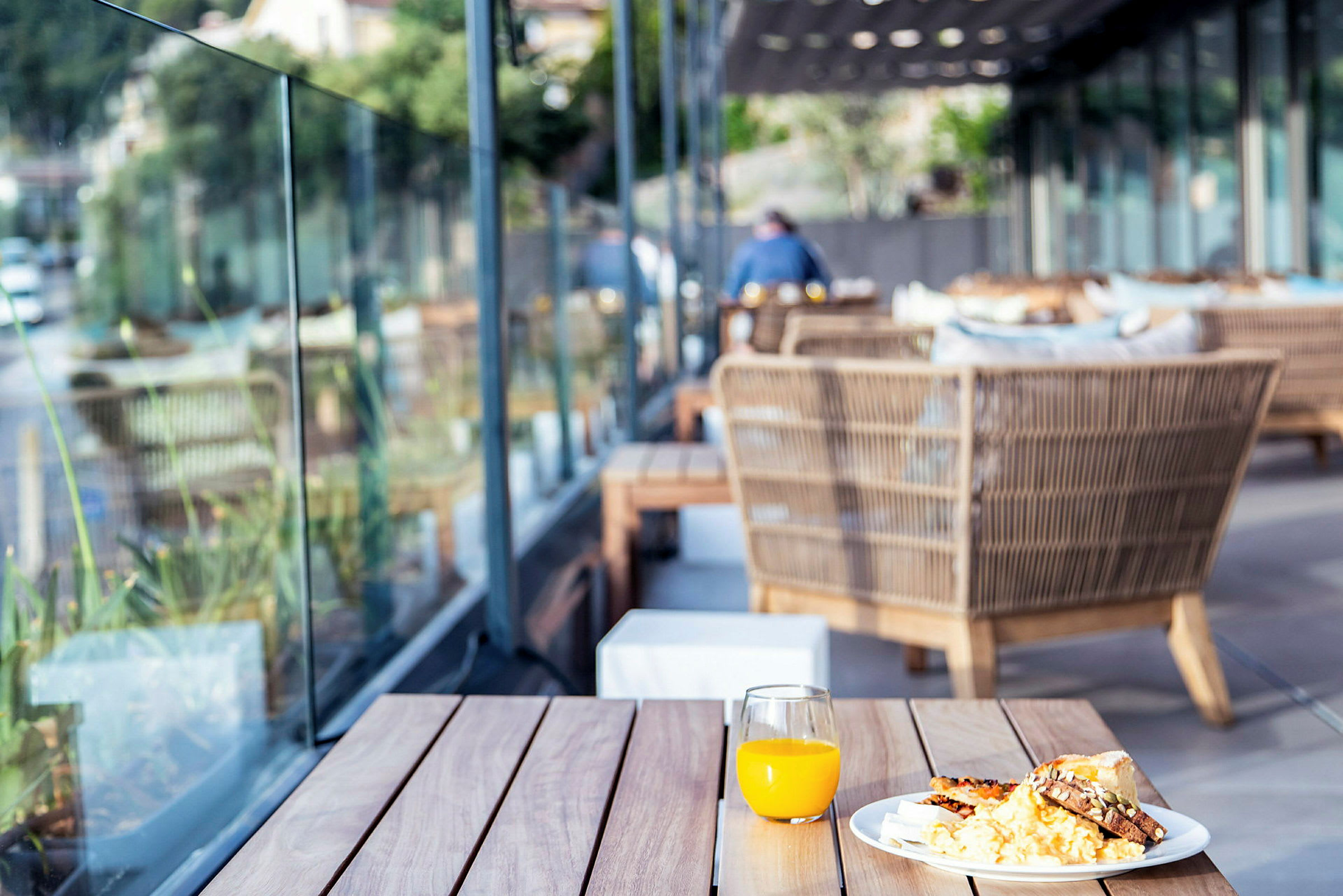 En tallrik med mat och ett glas med apelsinjuice på ett bord utomhus. (AI-genererad text)