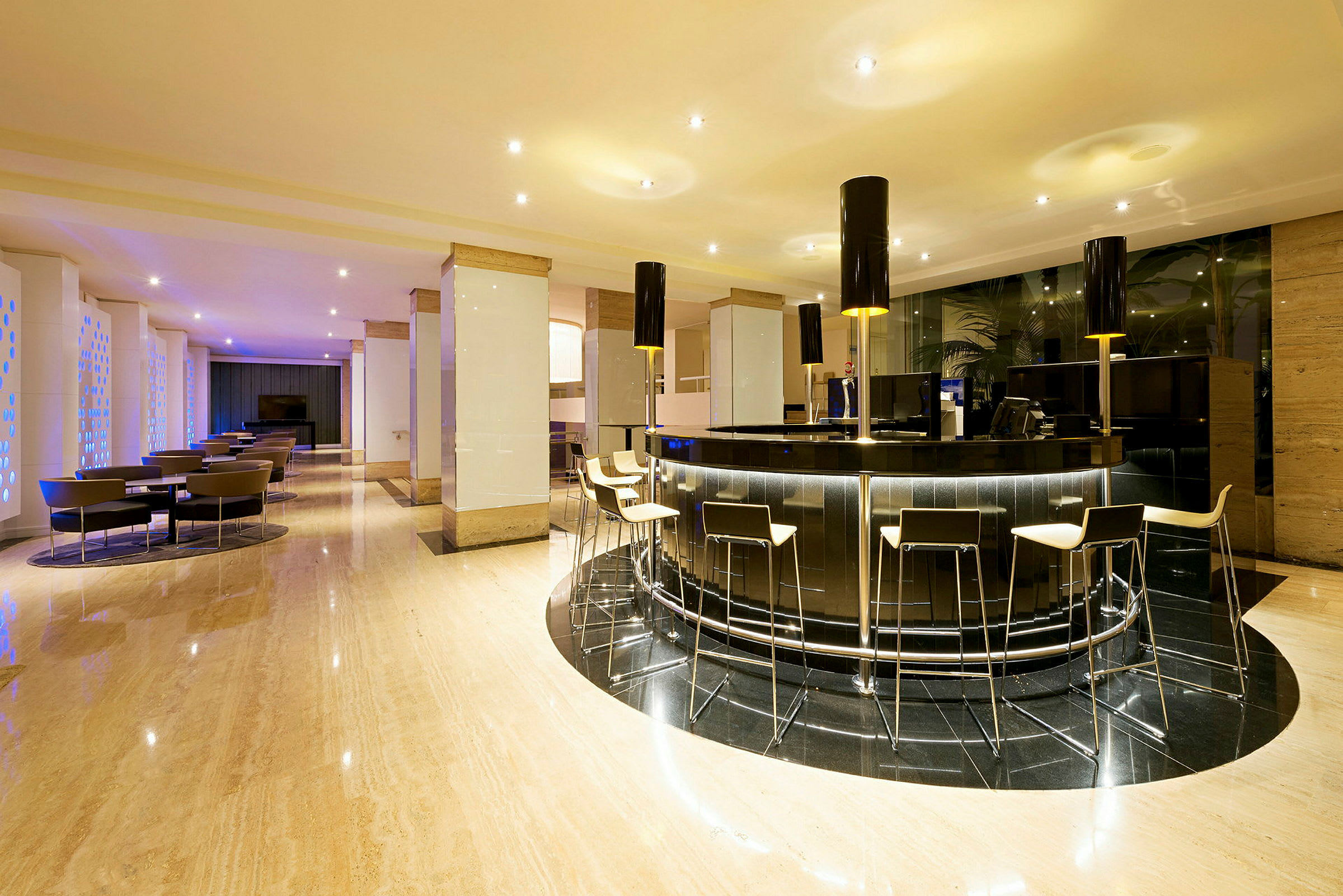 En modern hotellobby med en stilren bardisk och barstolar. Stolar och bord finns placerade i bakgrunden. (AI-genererad text)