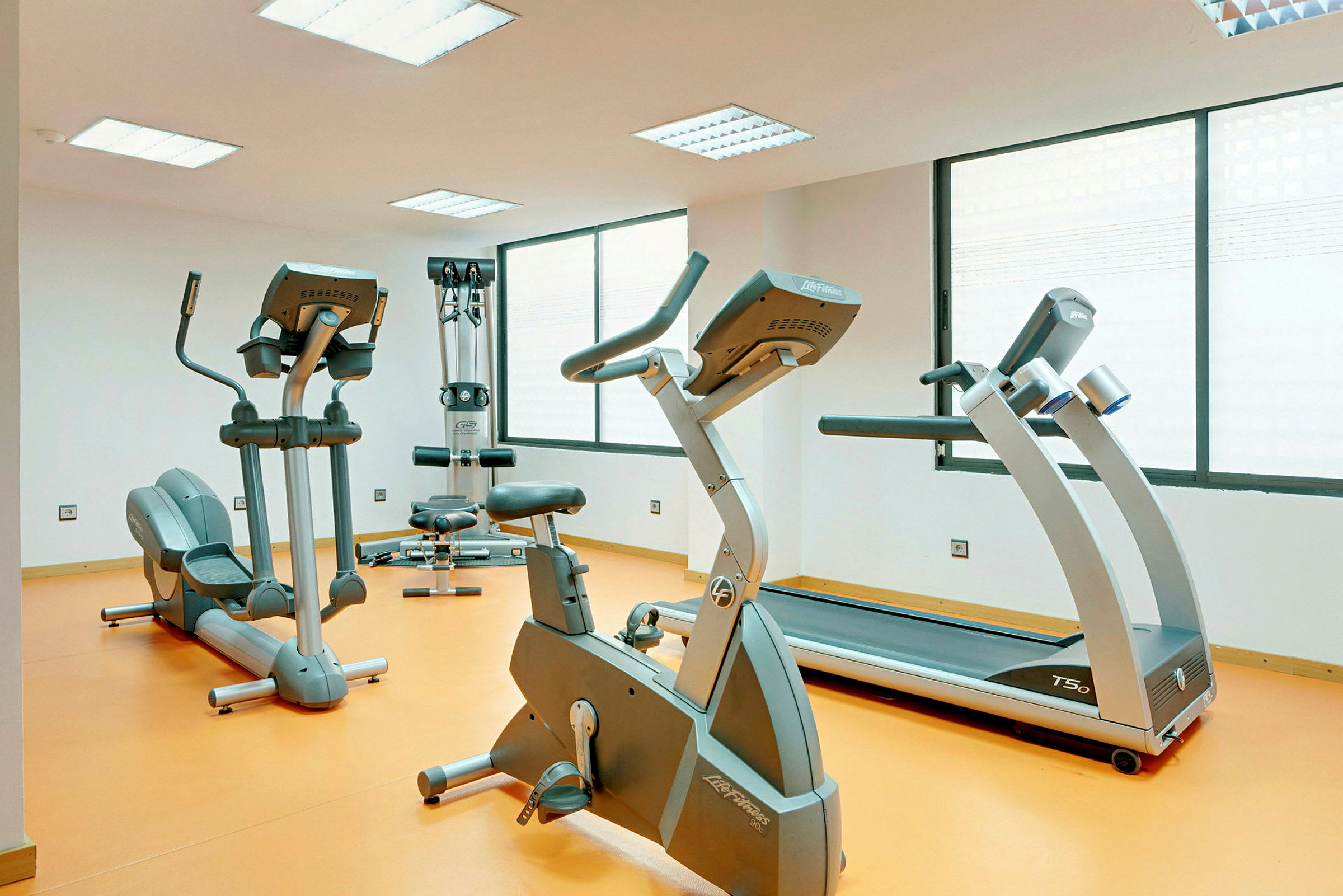 Bild av ett gym med träningsmaskiner såsom löpband, cykel och andra redskap. (AI-genererad text)