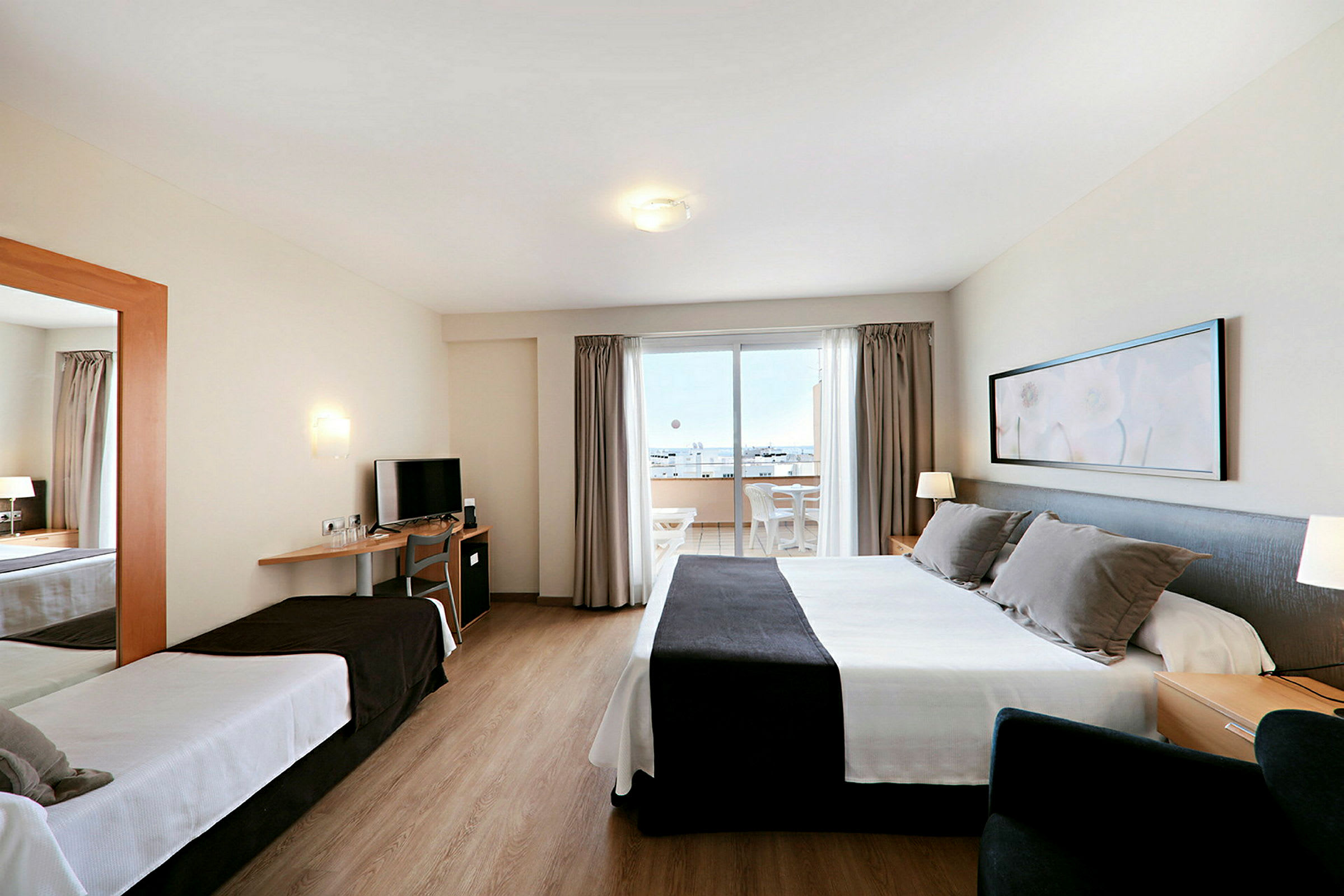 Ett hotellrum med två sängar, en TV och en balkong med utsikt. (AI-genererad text)