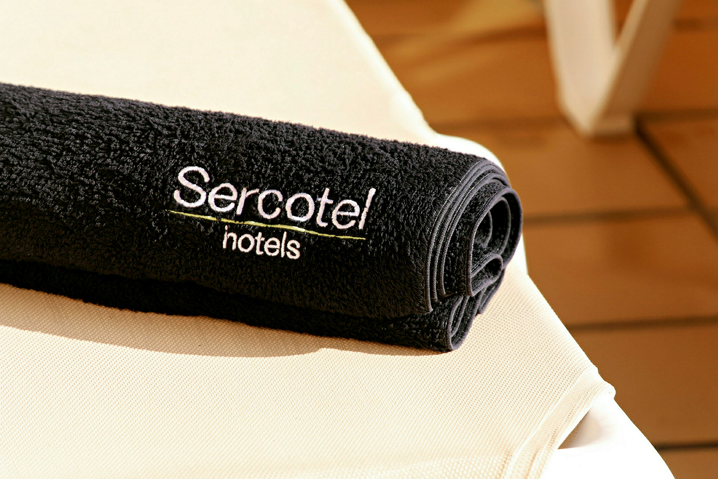 En svart handduk med texten 'Sercotel hotels' broderad, placerad på en ljus yta. (AI-genererad text)