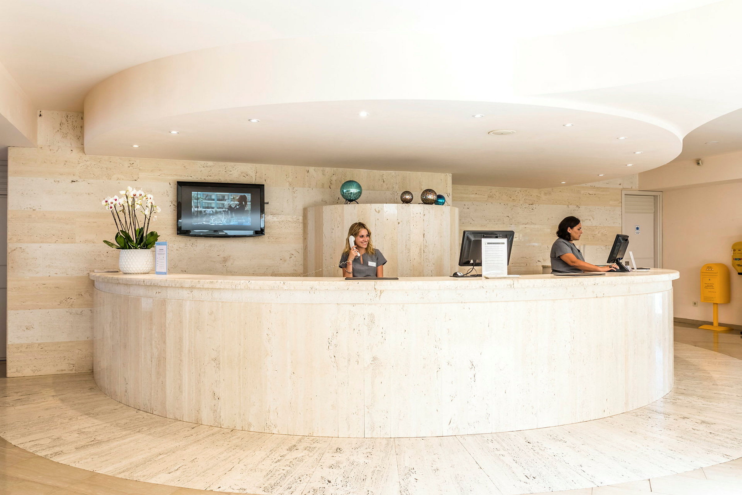 Reception som bemannas av två personer, med en böjd disk och dekorativa föremål. (AI-genererad text)