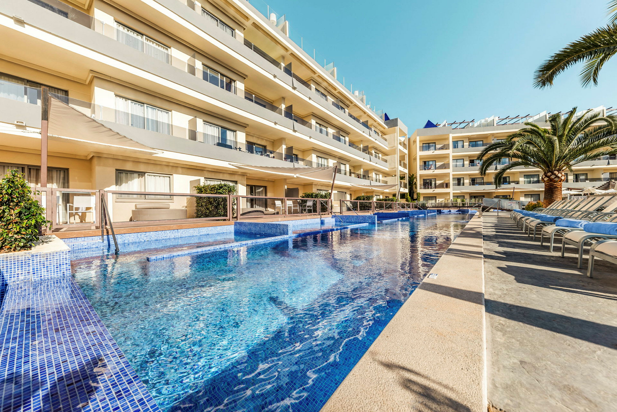 En utomhuspool vid ett hotellområde med flera våningar och balkonger. (AI-genererad text)