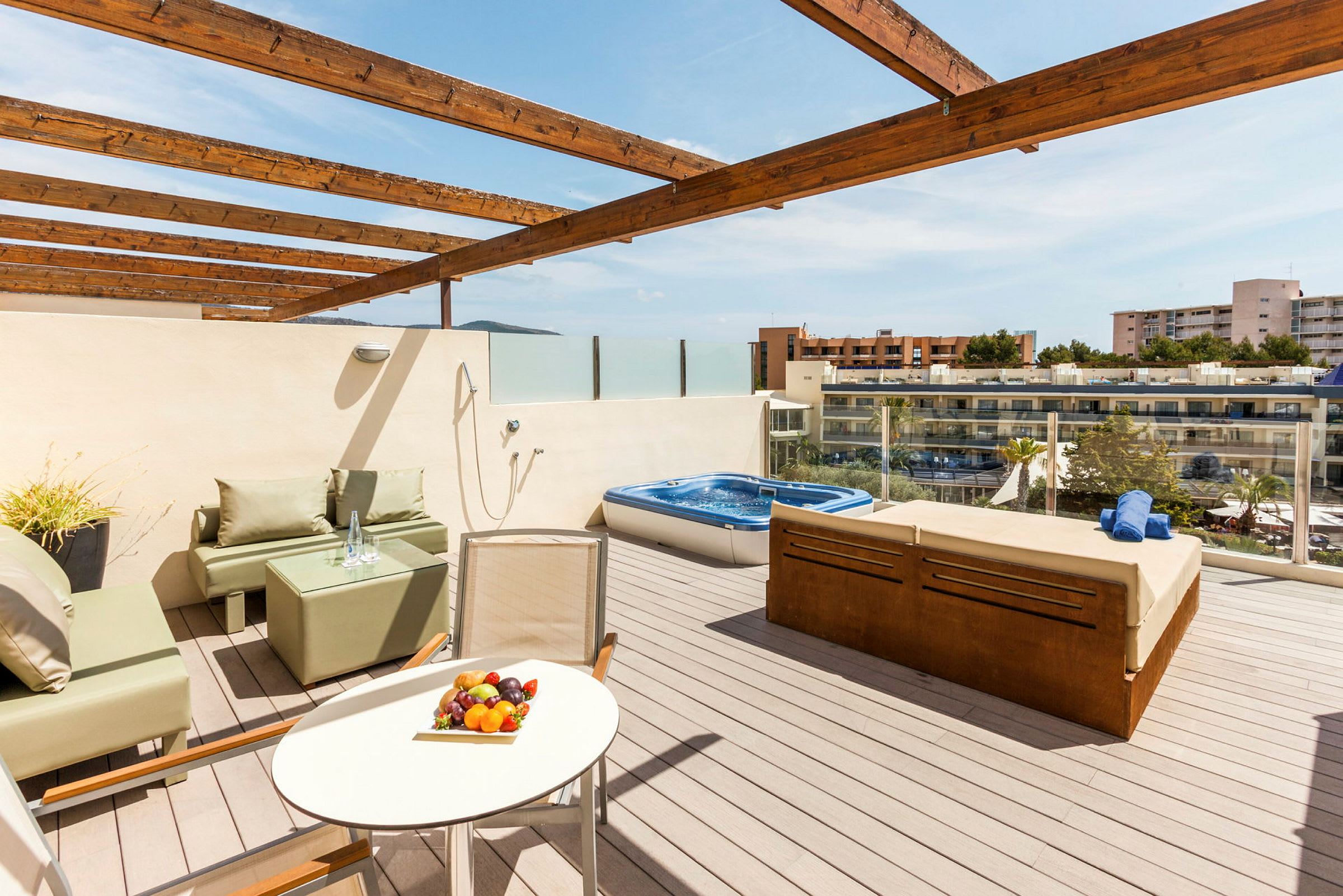 En terrass med en jacuzzi, sittmöbler och utsikt över omgivande byggnader. (AI-genererad text)