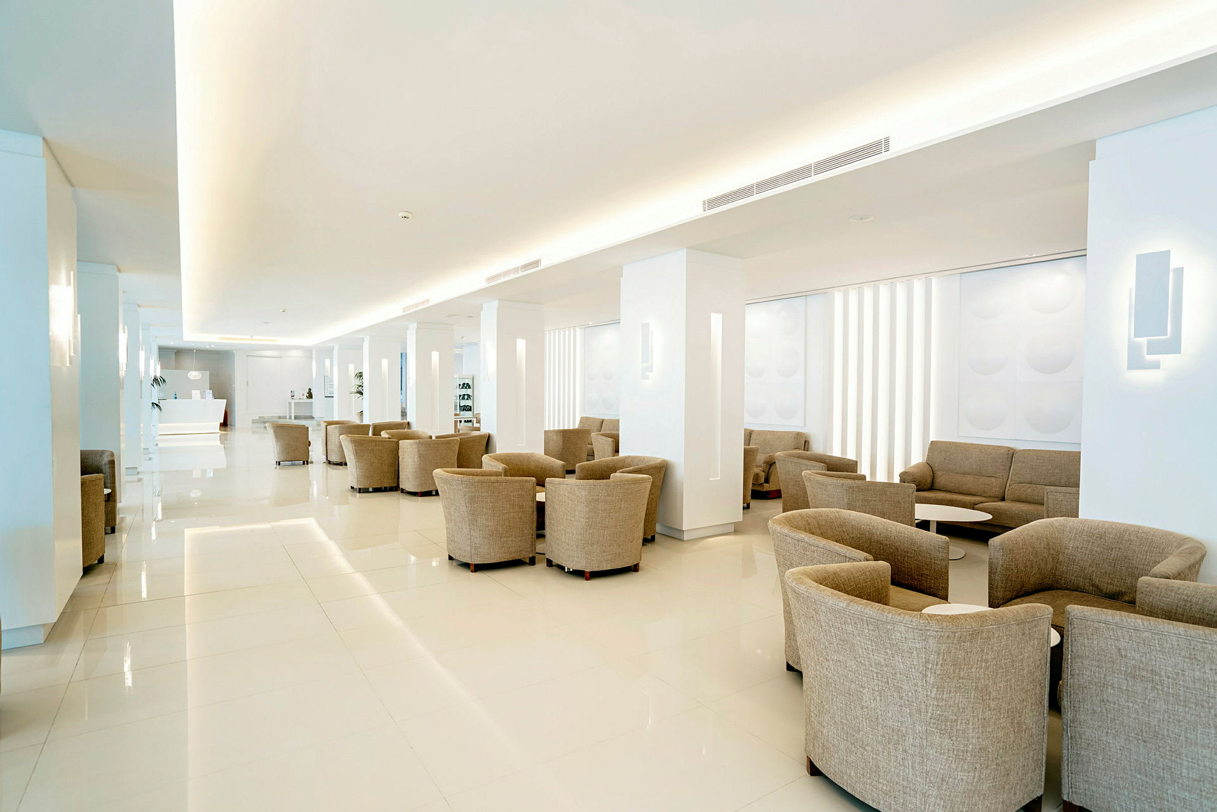 En rymlig och ljus hotellobby med beige sittplatser. (AI-genererad text)