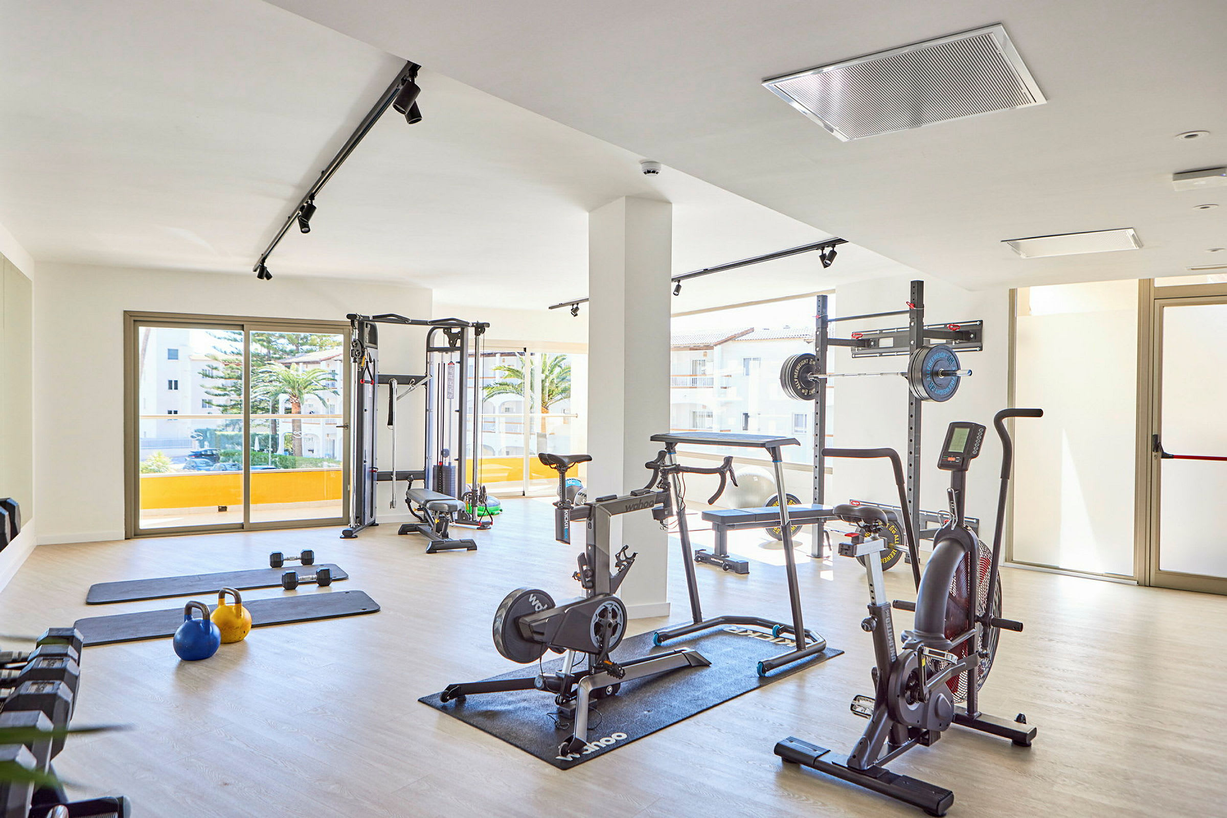 Ett gym med olika träningsutrustningar placerade i ett ljust rum. (AI-genererad text)