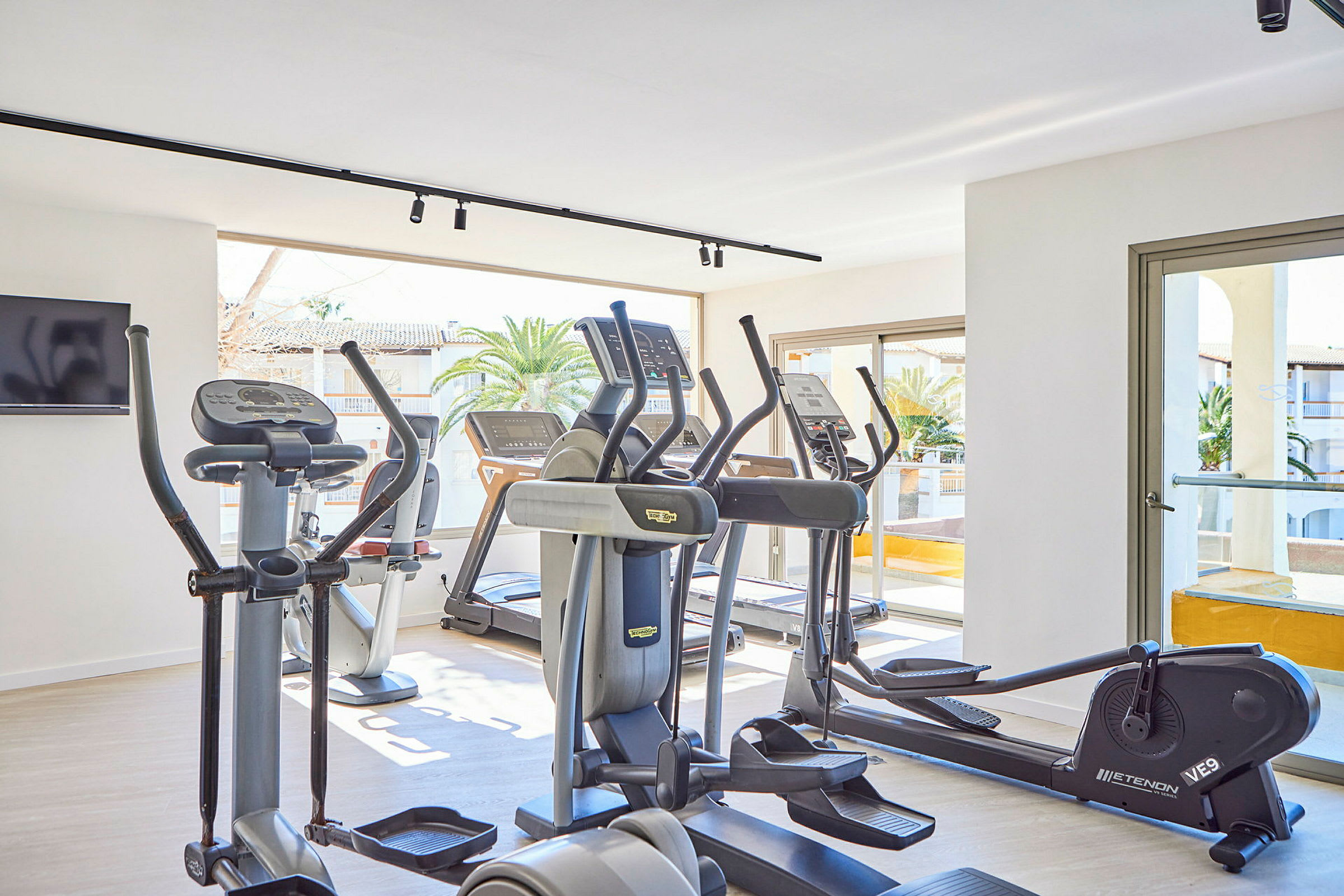 Ett gym med moderna träningsmaskiner och stora fönster. (AI-genererad text)
