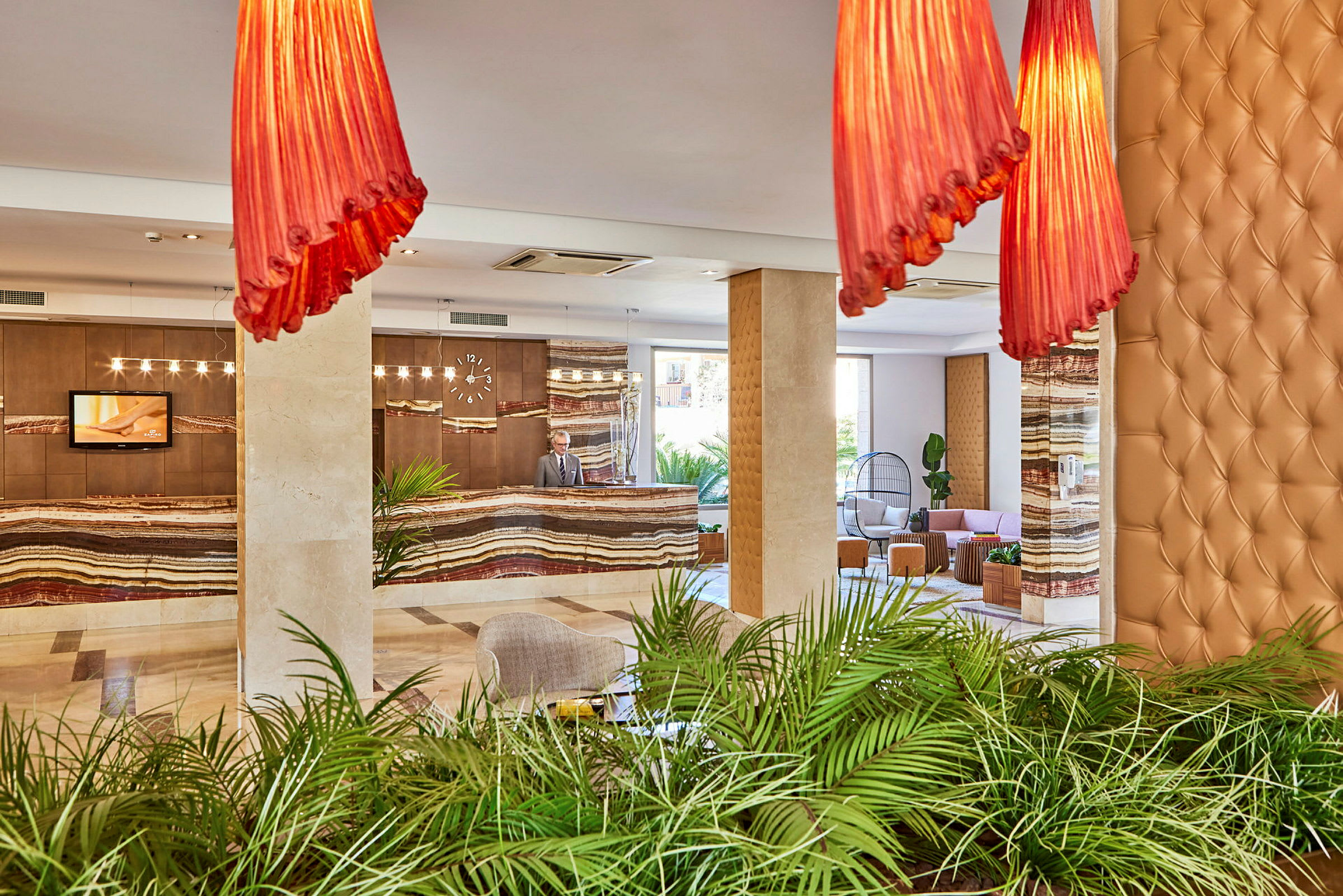 Hotellobby med reception, gröna växter och sittplatser. (AI-genererad text)