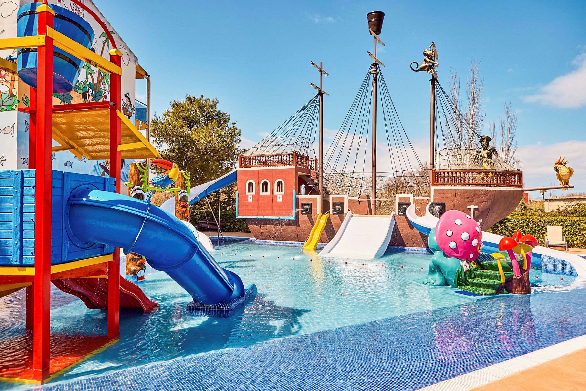 Bild av en vattenpark med ett pirattemat skepp, färgglada rutschkanor och lekskulpturer i en pool. (AI-genererad text)