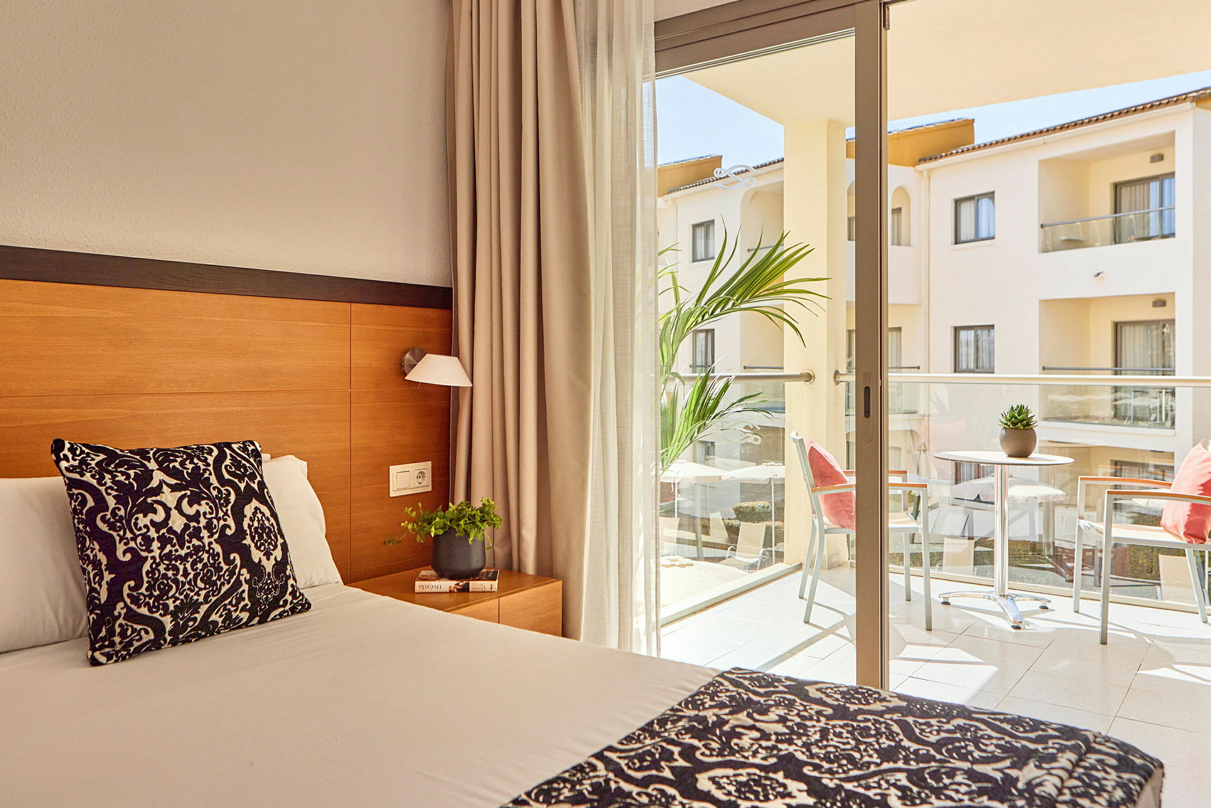 Hotellrum med säng och balkong med möbler. (AI-genererad text)