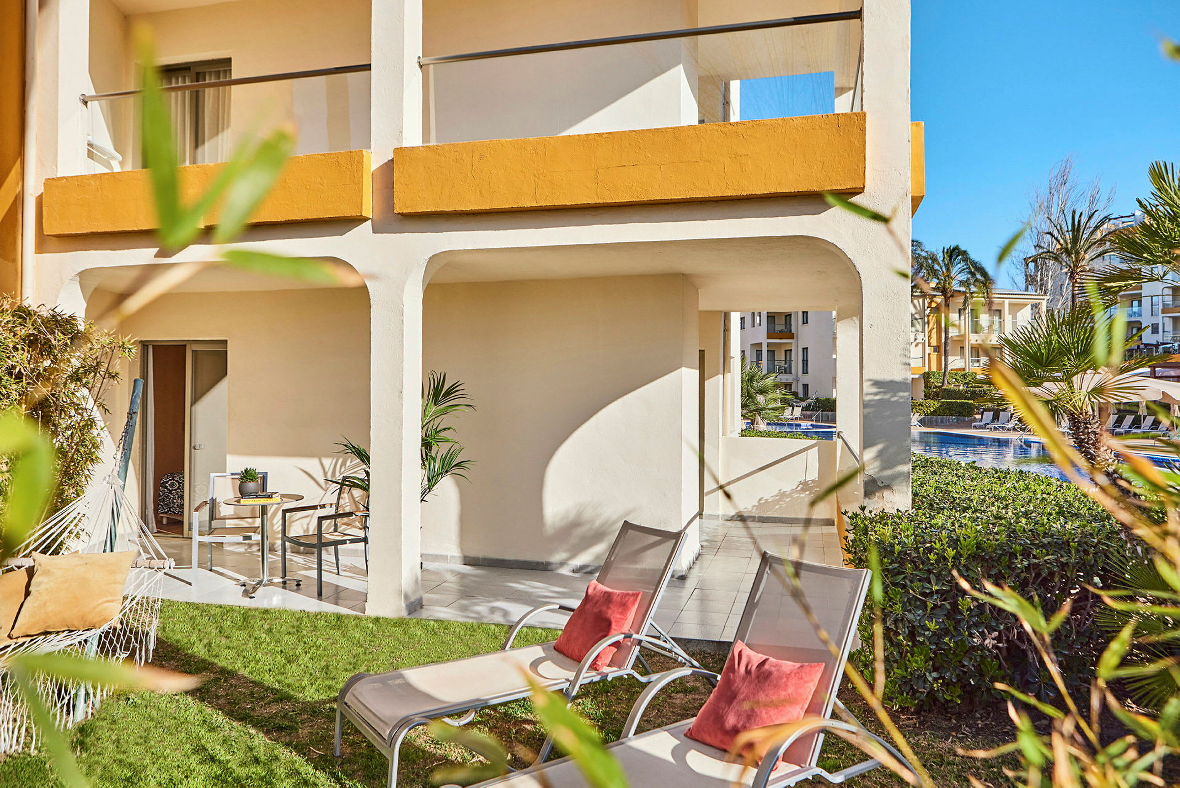 Uteplats med gräsmatta, solstolar och parasoll vid ett hotell. (AI-genererad text)