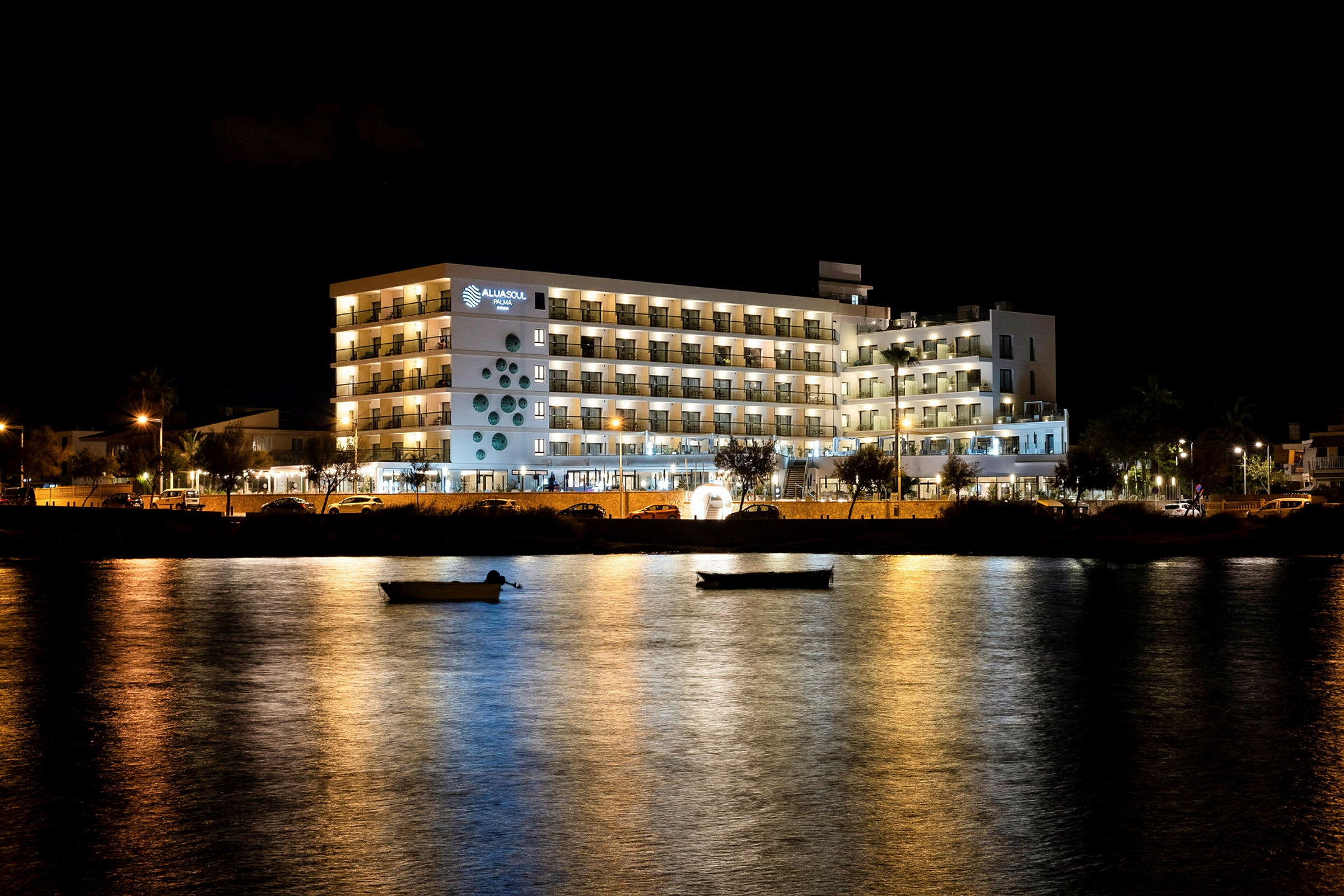 Hotell byggt med upplysta balkonger vid vattnet på kvällen. (AI-genererad text)