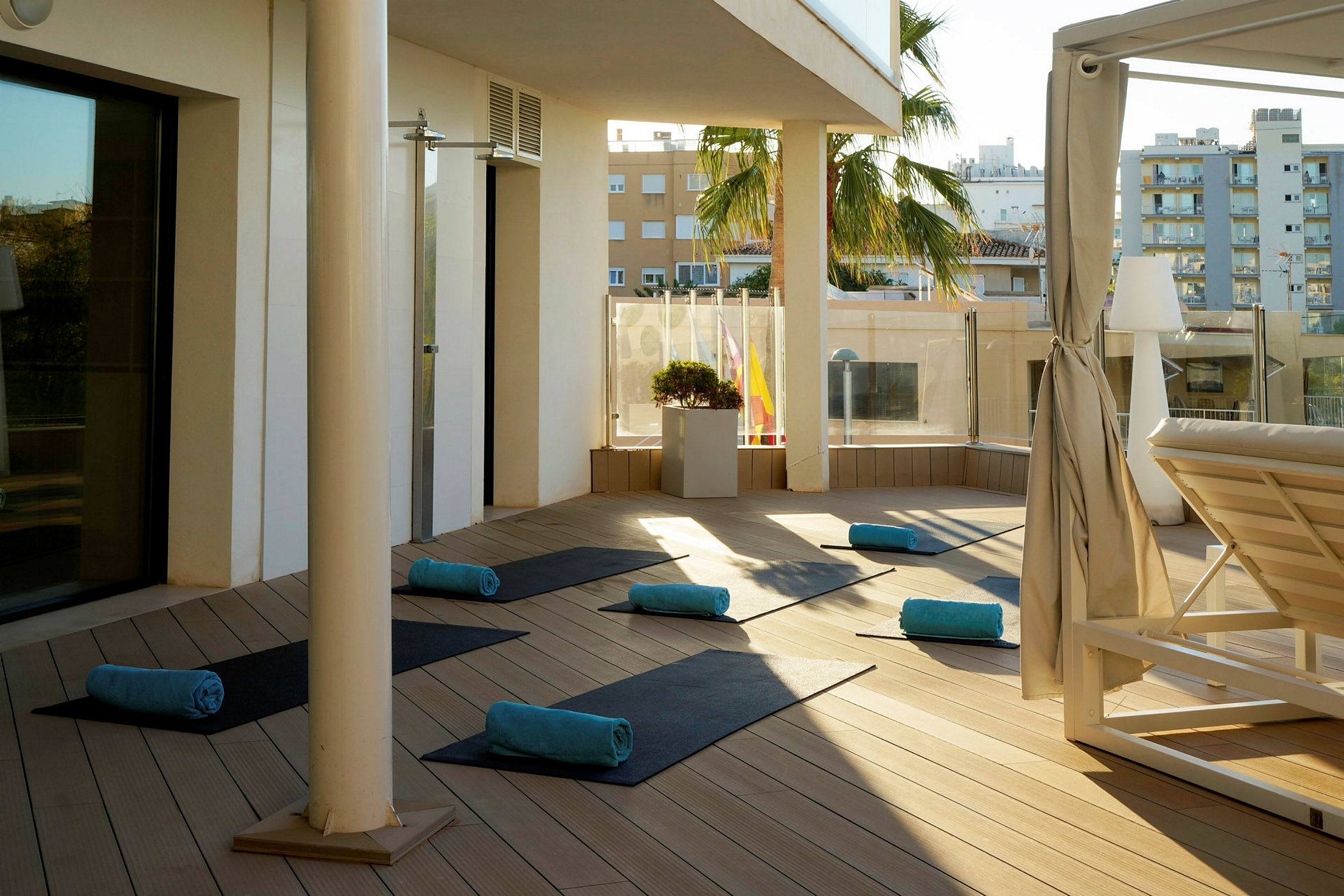 Solbelyst terrass med utrullade yogamattor och handdukar. (AI-genererad text)
