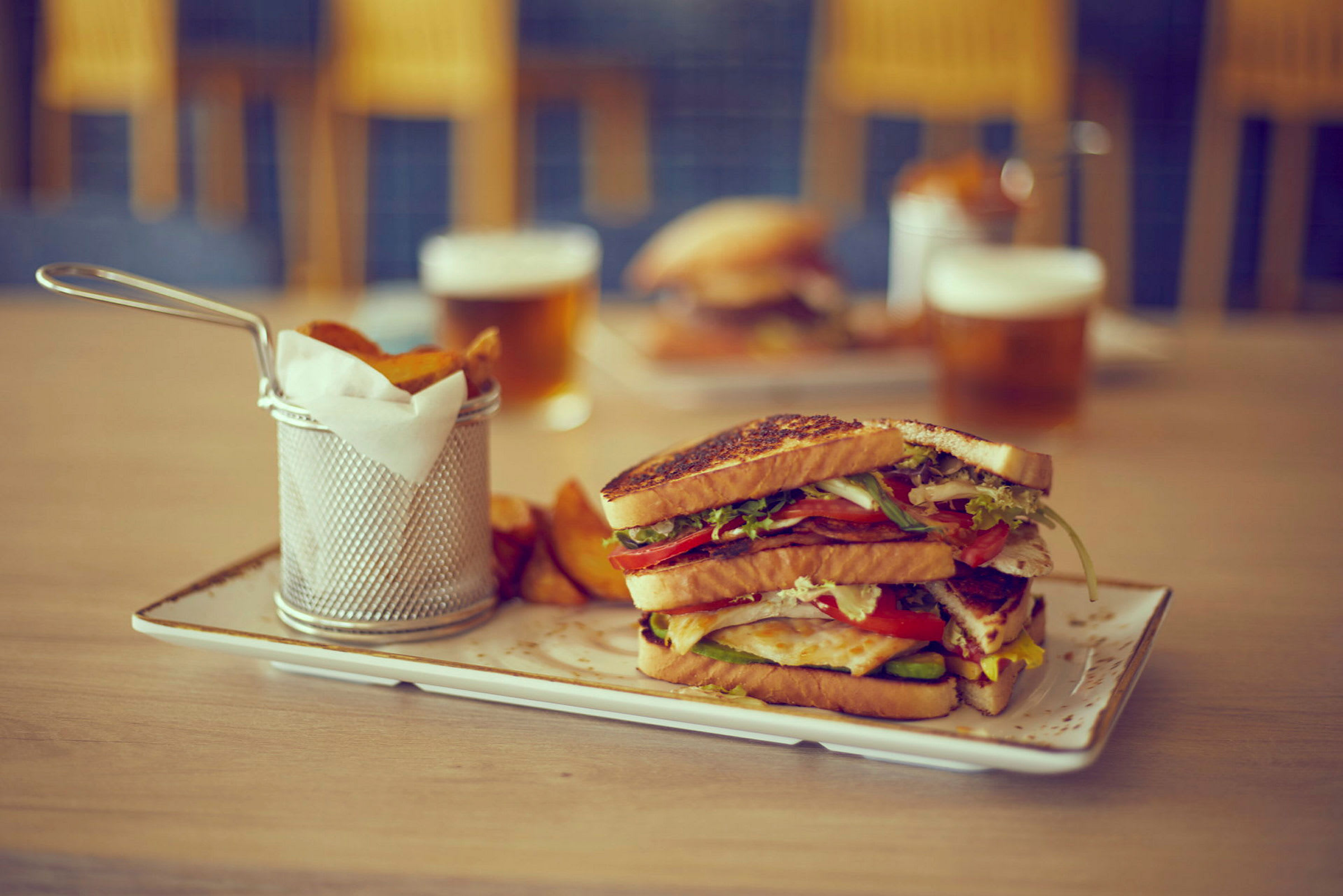 En tallrik med en sandwich och pommes frites bredvid en dryck. (AI-genererad text)