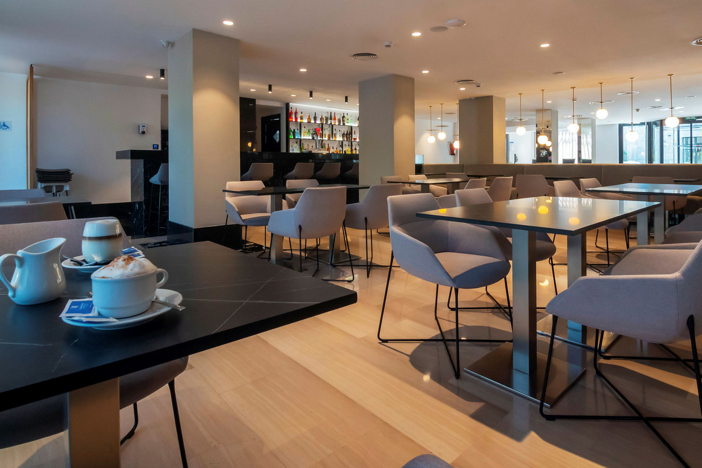Bild av en modern restaurang med bord och stolar samt en bardisk i bakgrunden. (AI-genererad text)