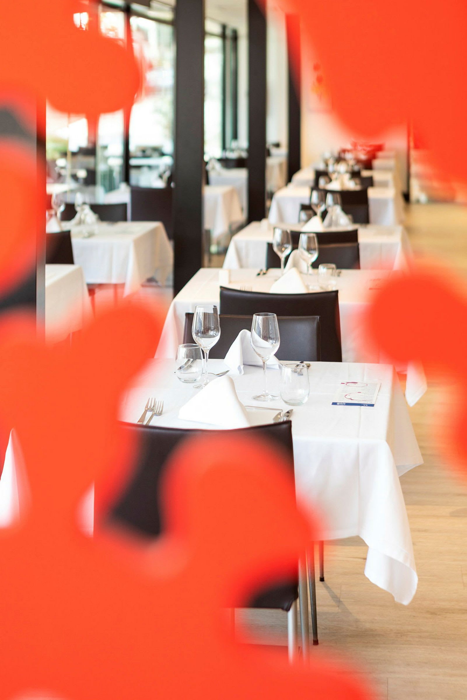 Elegant restaurang med dukade bord och vita borddukar, sedd genom röd dekoration. (AI-genererad text)