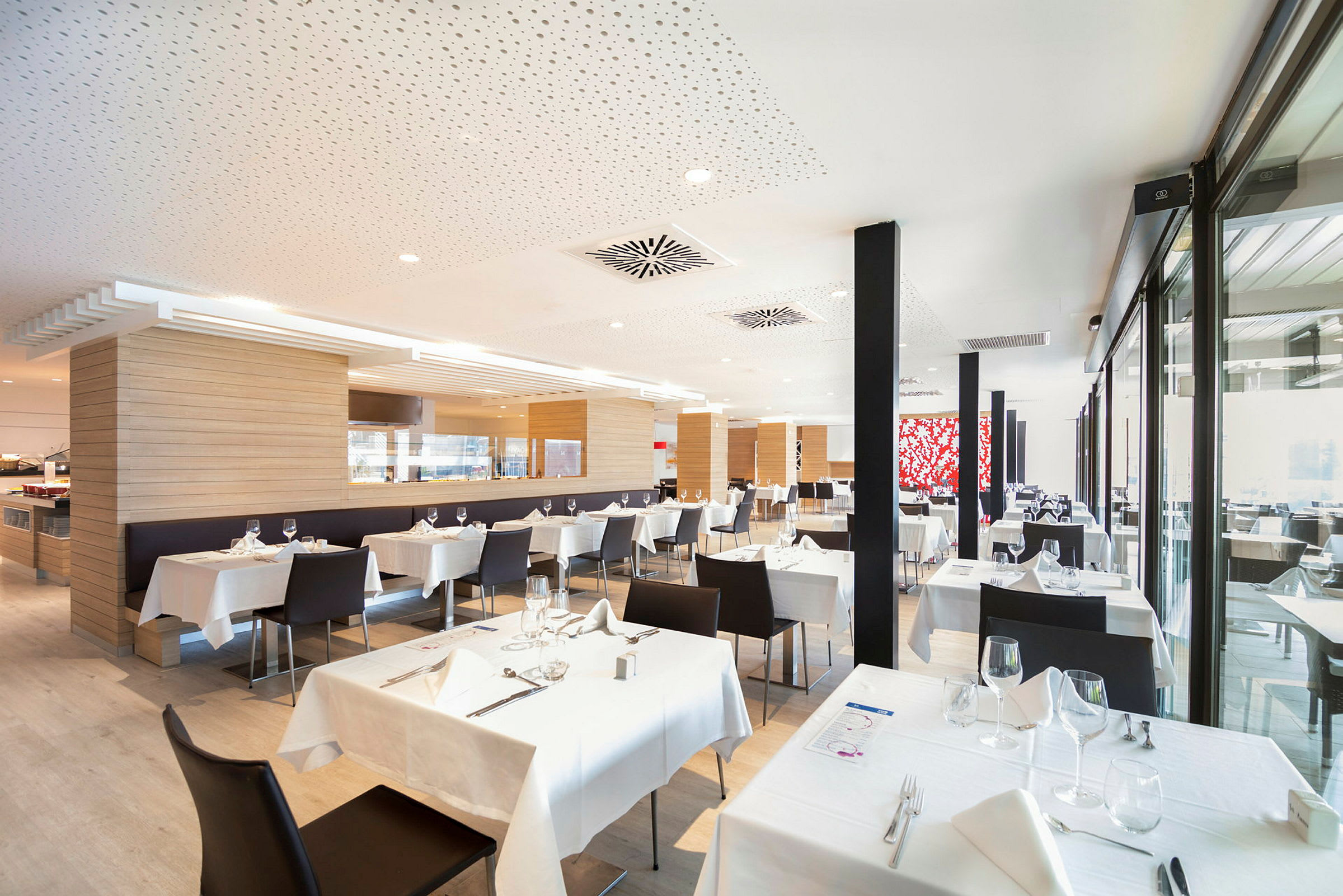 En modern restaurang med bord klädda i vita dukar och svarta stolar. (AI-genererad text)