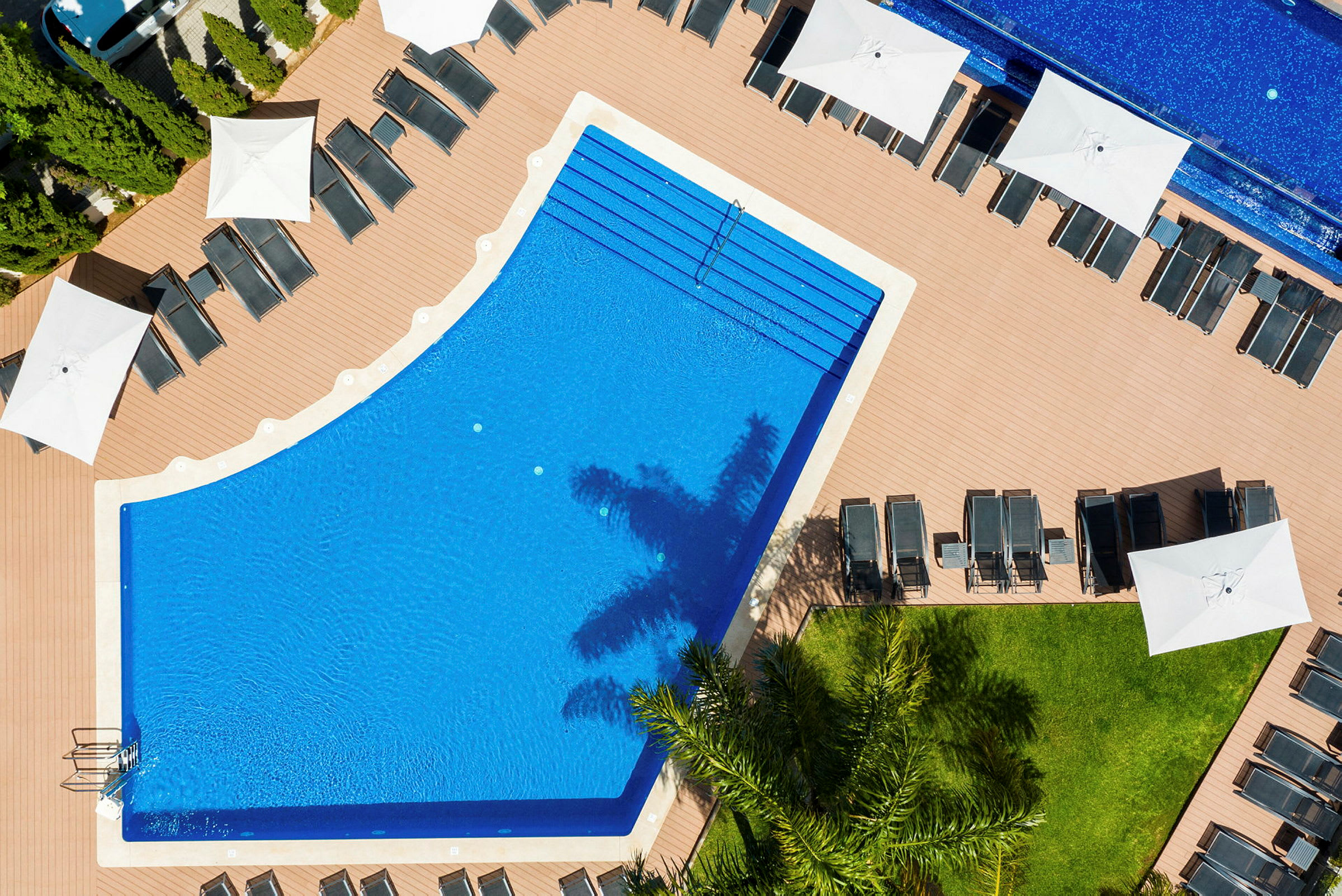 Flygfoto av en pool omringad av solstolar och parasoller. (AI-genererad text)