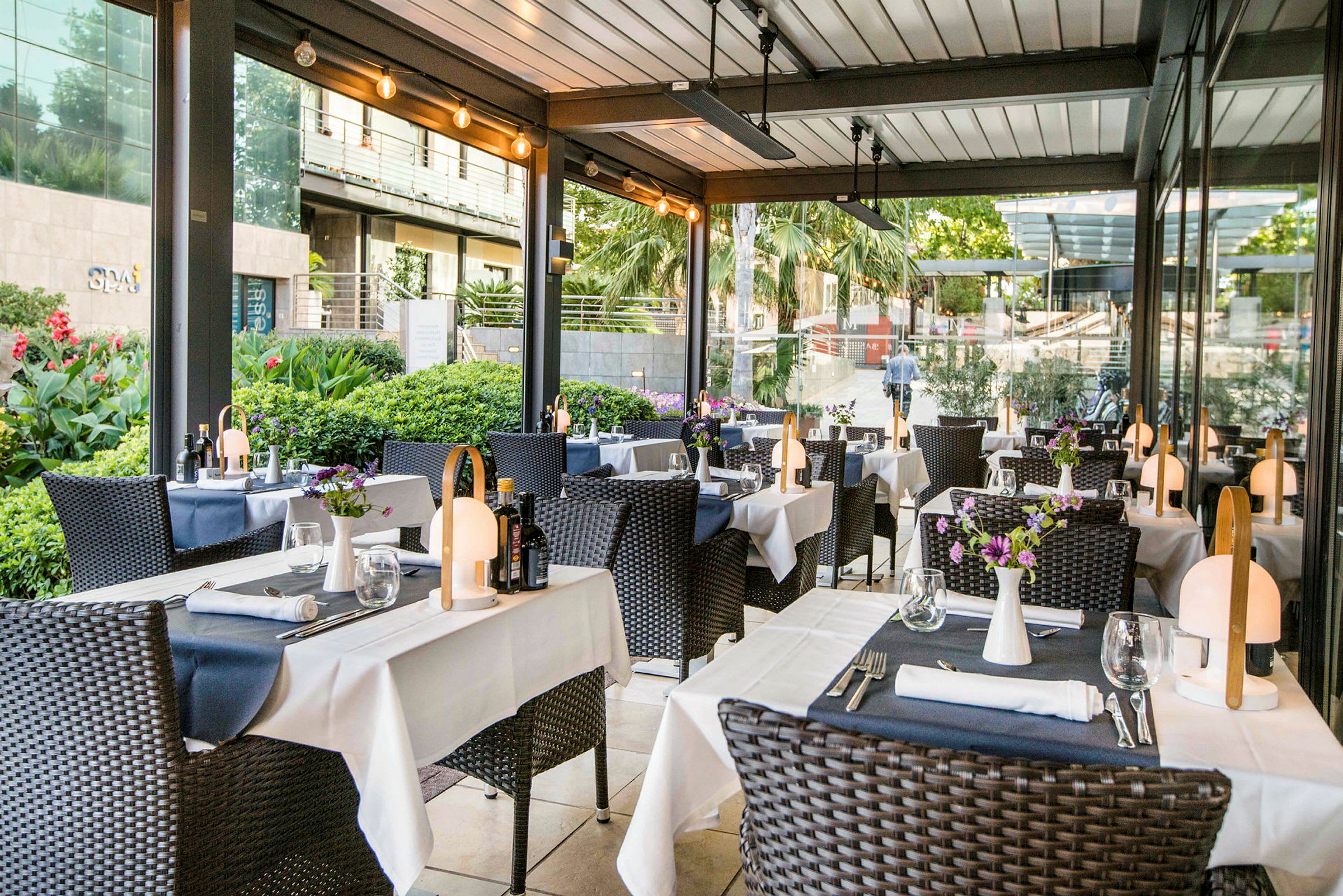 Utomhusrestaurang med dukade bord och dekorerade stolar. (AI-genererad text)