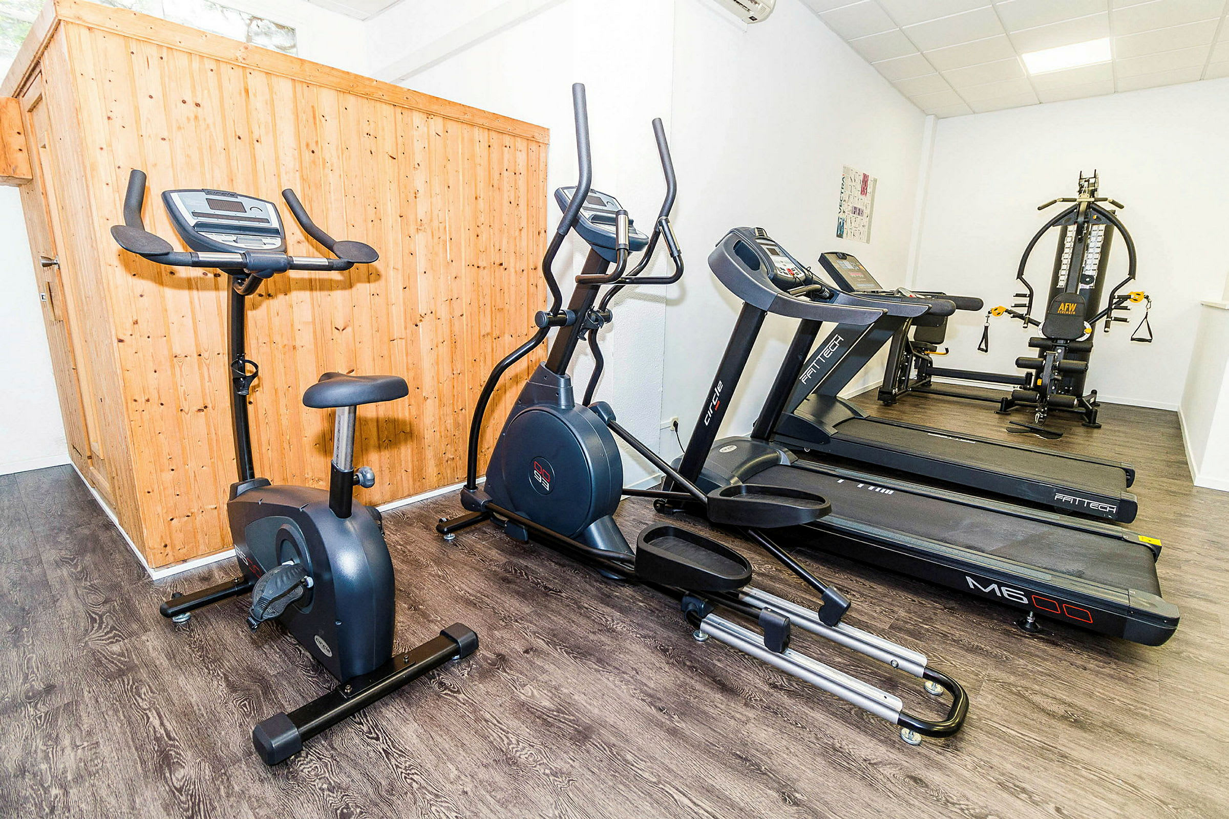 Träningsutrustning inklusive en motionscykel, en crosstrainer och flera löpband i ett gym. (AI-genererad text)