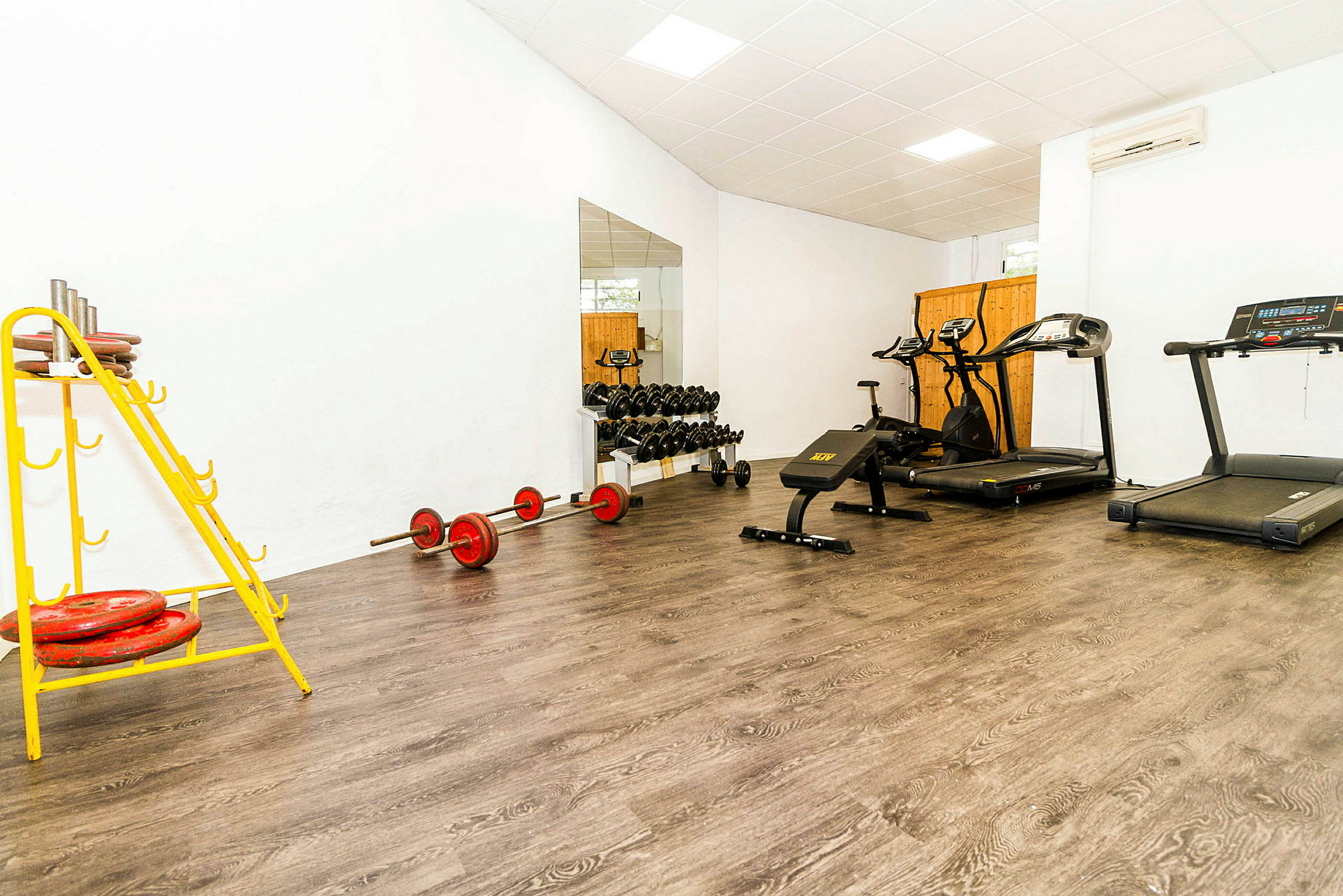 Gymrum med träningsutrustning som löpband, vikter och en träningsbänk. (AI-genererad text)