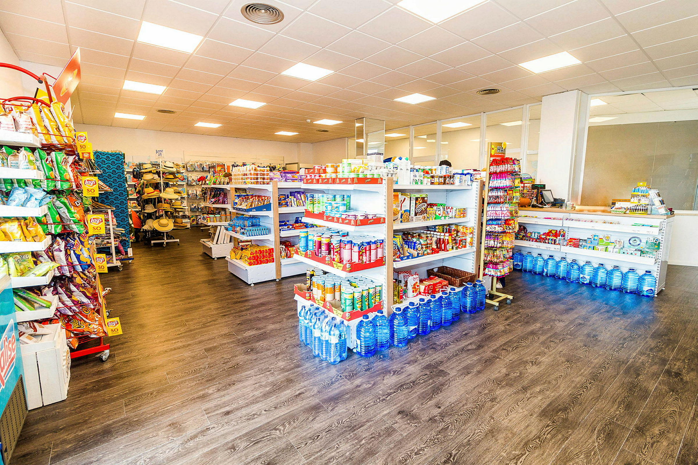 En butik med hyllor fyllda med dagligvaror som snacks, vattenflaskor och andra matvaror. (AI-genererad text)