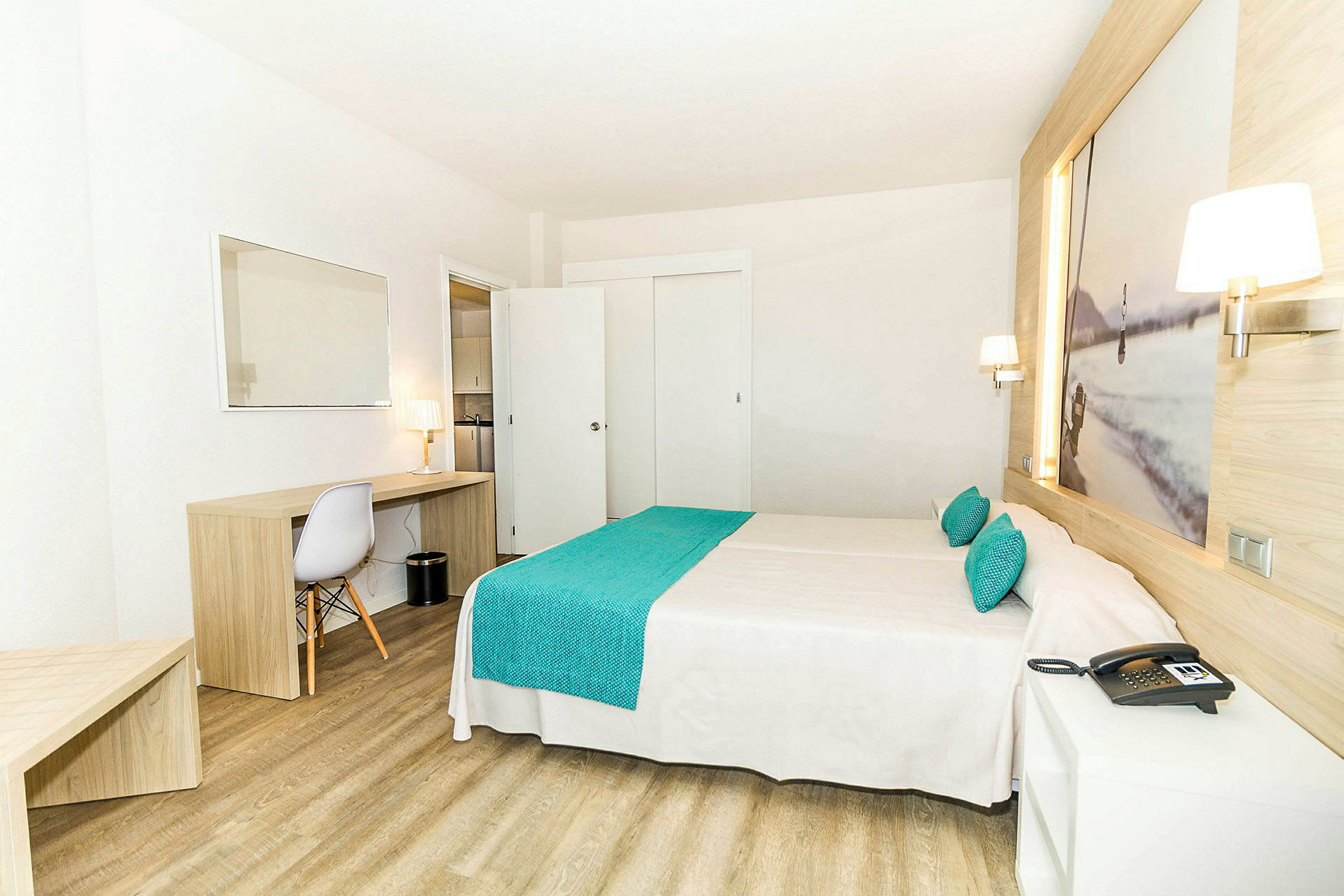 Ett hotellrum med en dubbelsäng, träinredning och en arbetsyta med en stol och en lampa. (AI-genererad text)