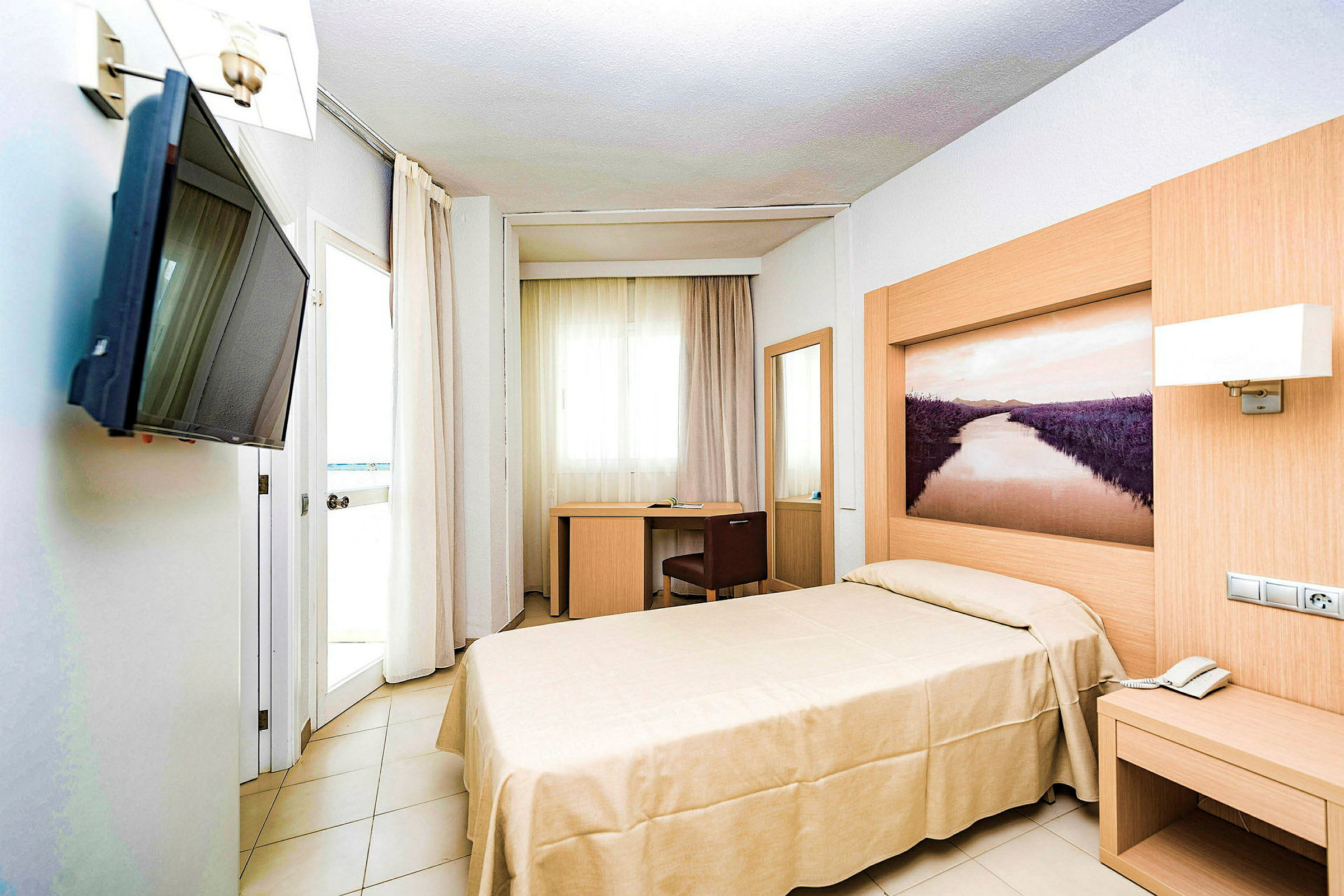 Ett hotellrum med en enkelsäng, skrivbord och vägg-TV. (AI-genererad text)