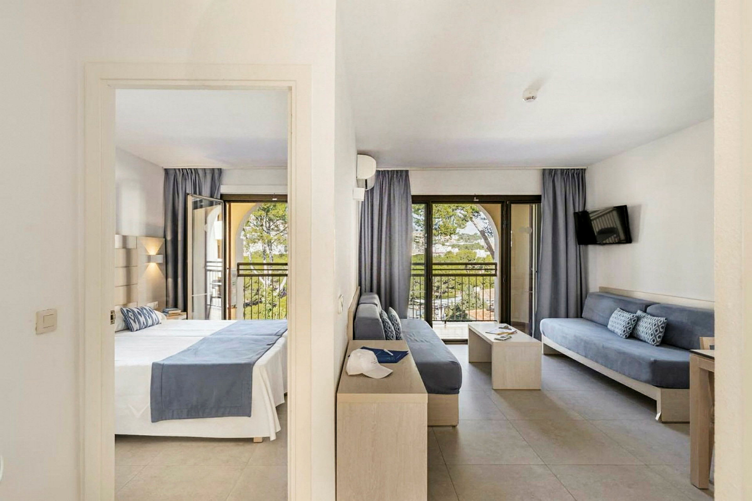 Bild av ett hotellrum med ett sovrum och ett vardagsrum, båda med tillgång till balkong. (AI-genererad text)