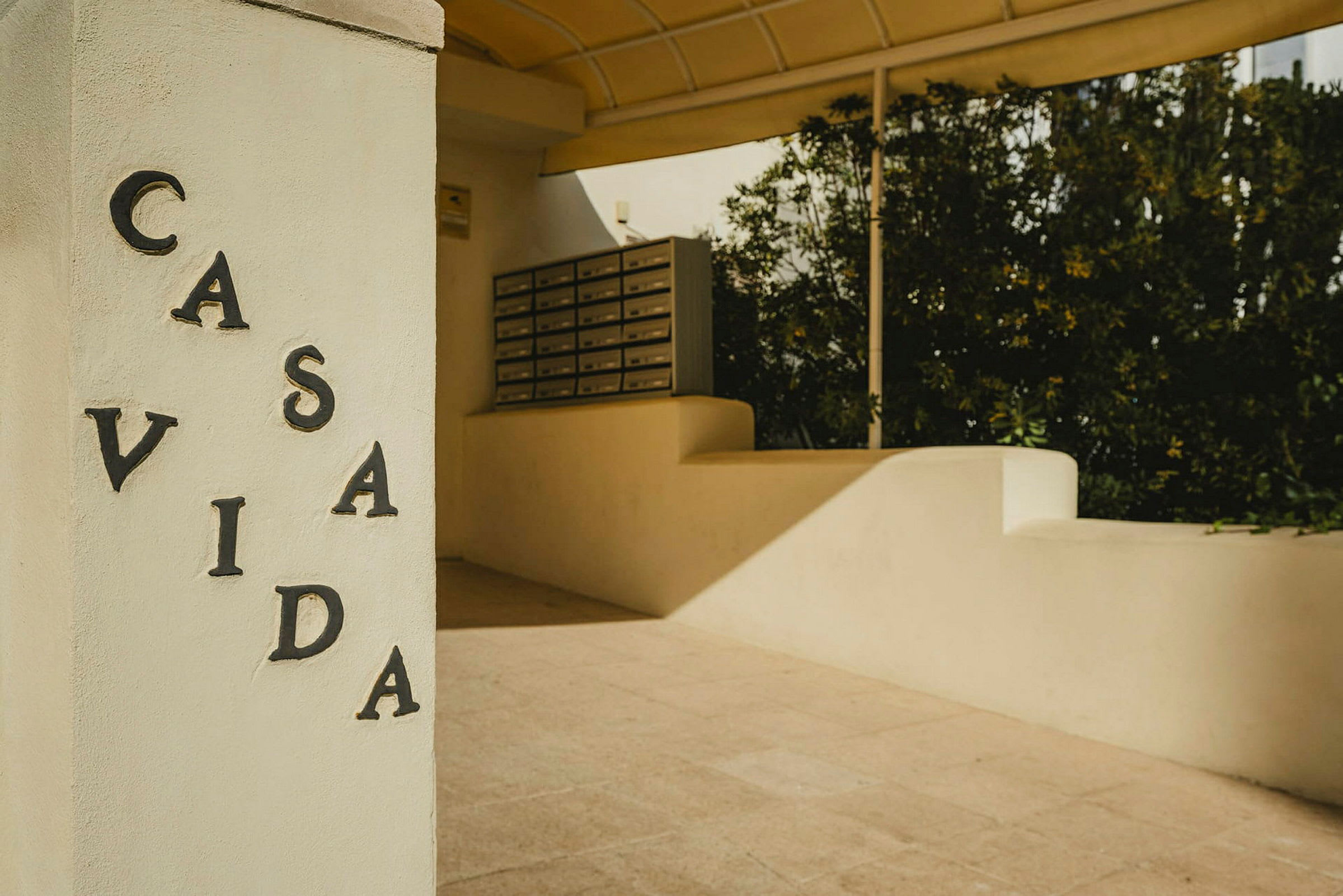 Ett vitt stenfundament med texten "CASA VIDA" samt postlådor i bakgrunden. (AI-genererad text)