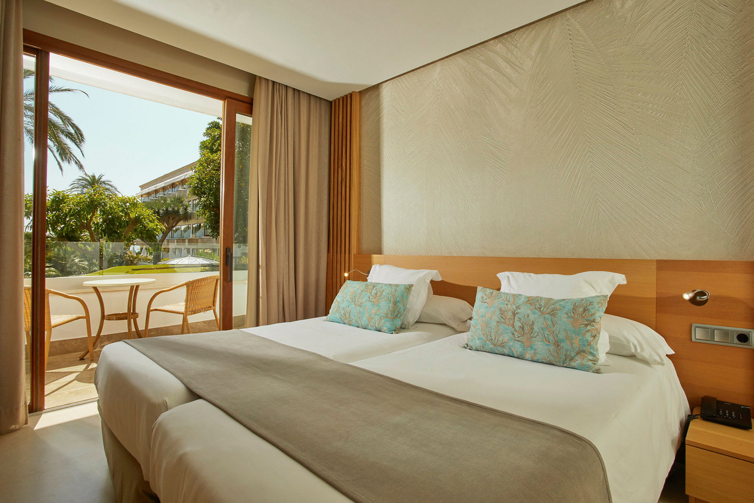 Hotellrum med två separata sängar och utsikt mot en möblerad balkong. (AI-genererad text)
