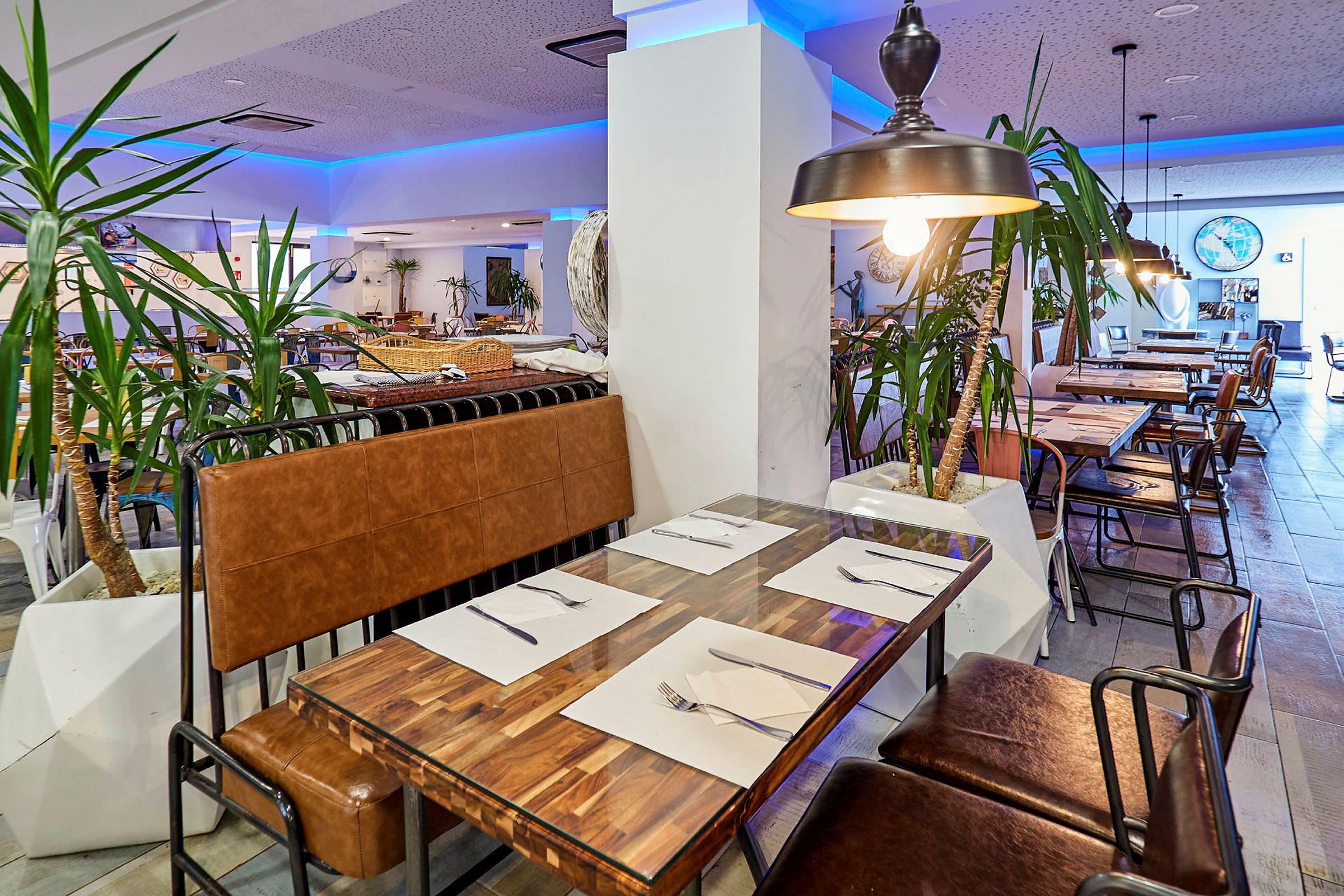 En restaurang interiör med bord och stolar, dekorerad med inomhusväxter och belysning. (AI-genererad text)