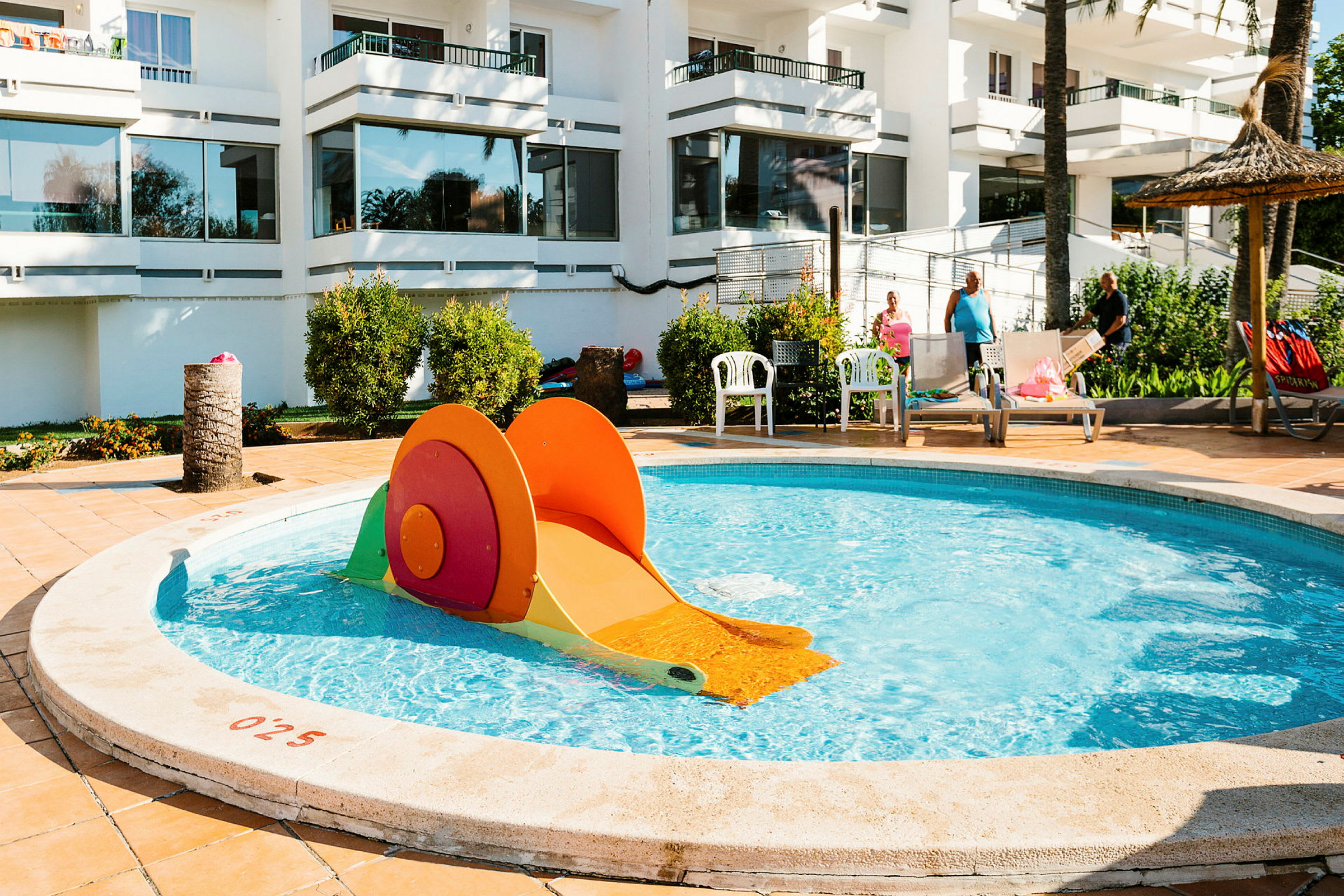 Barnpool med en färgglad rutschkana vid ett hotell. (AI-genererad text)