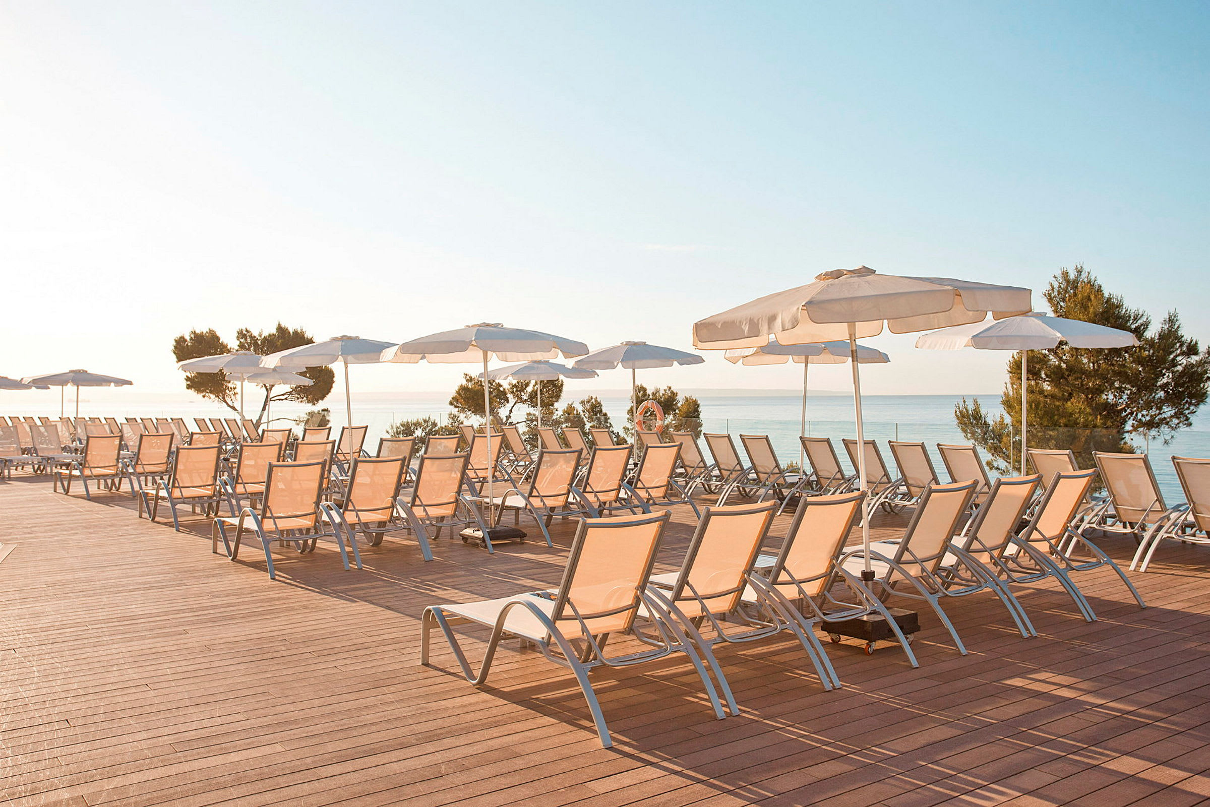 Solstolar och parasoller på en terrass med utsikt över havet. (AI-genererad text)