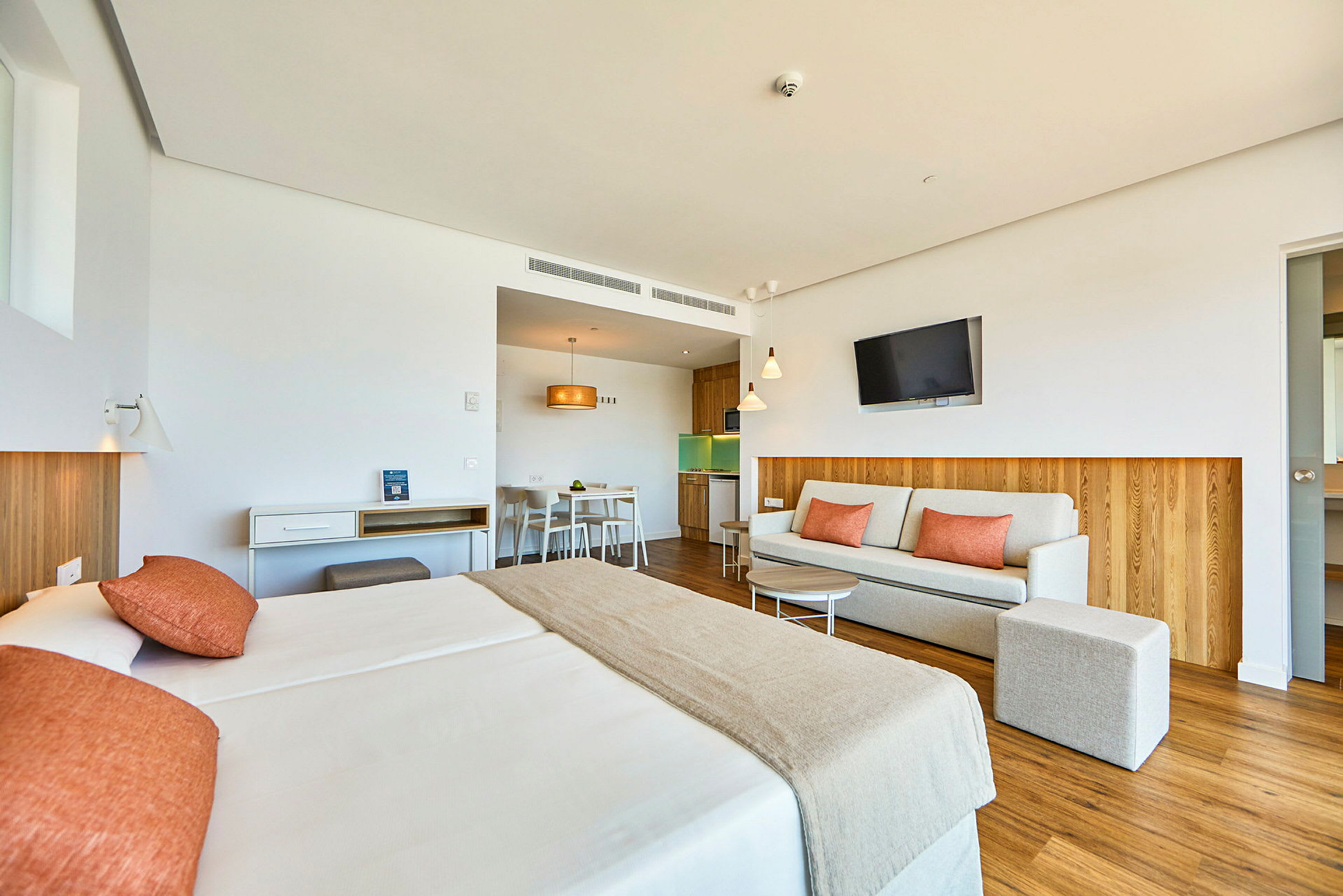 Ett hotellrum med en säng, en soffa och ett kök. (AI-genererad text)