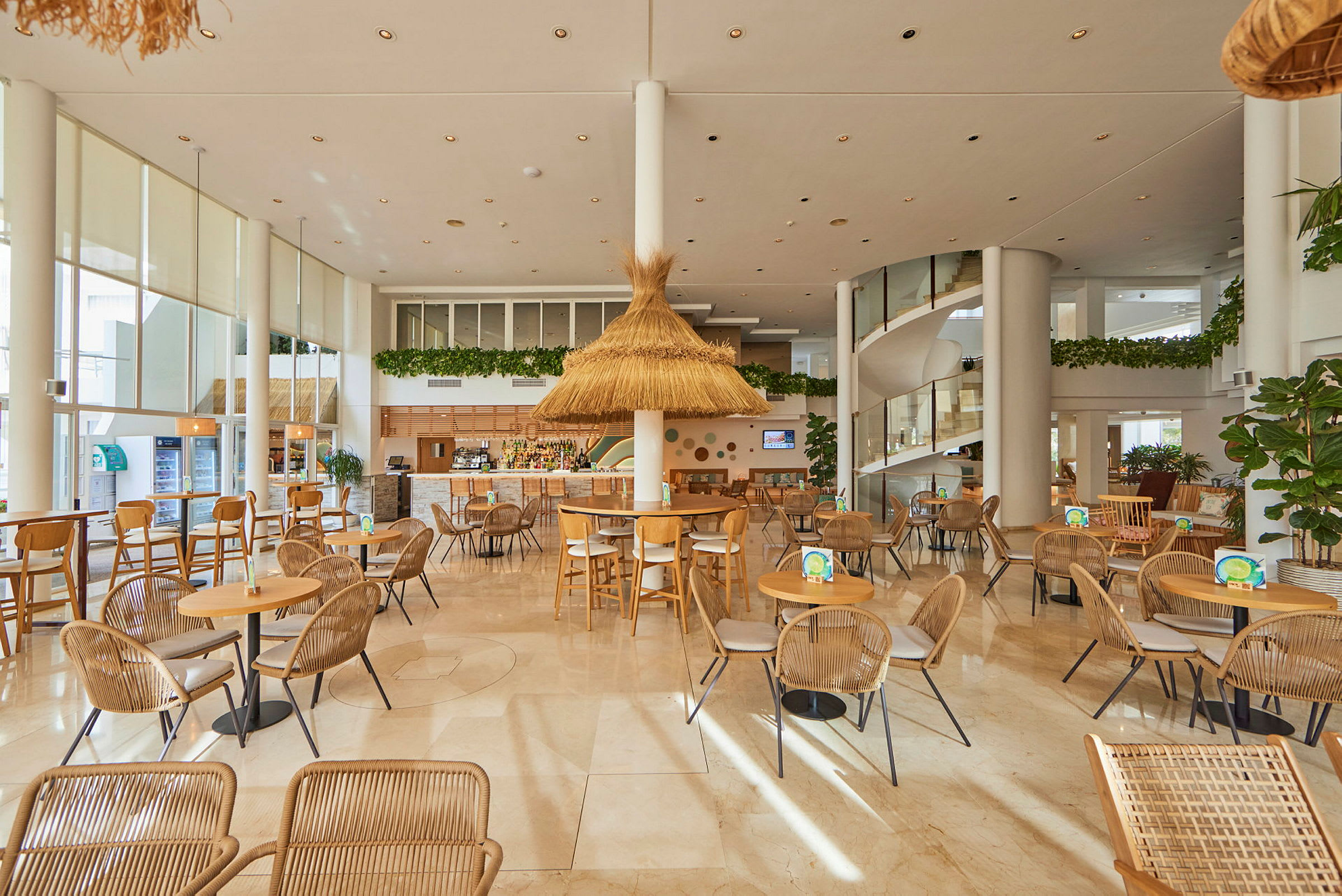 Interiörbild av en rymlig, ljus restaurang med träbord, rottingstolar och växtdekor. (AI-genererad text)